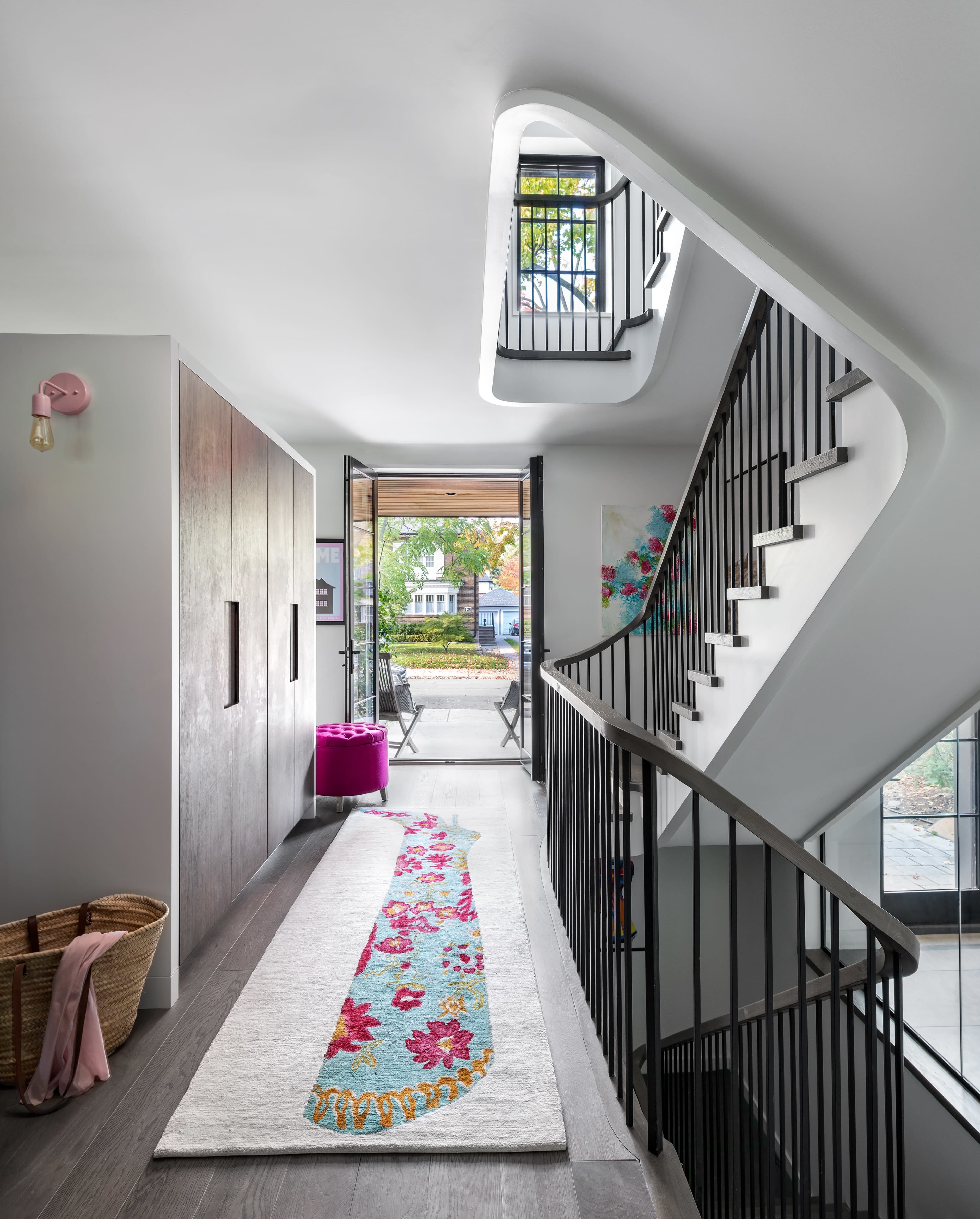 A modern entryway with a staircase, a decorative runner on the floor, and a door that opens to an outdoor space.