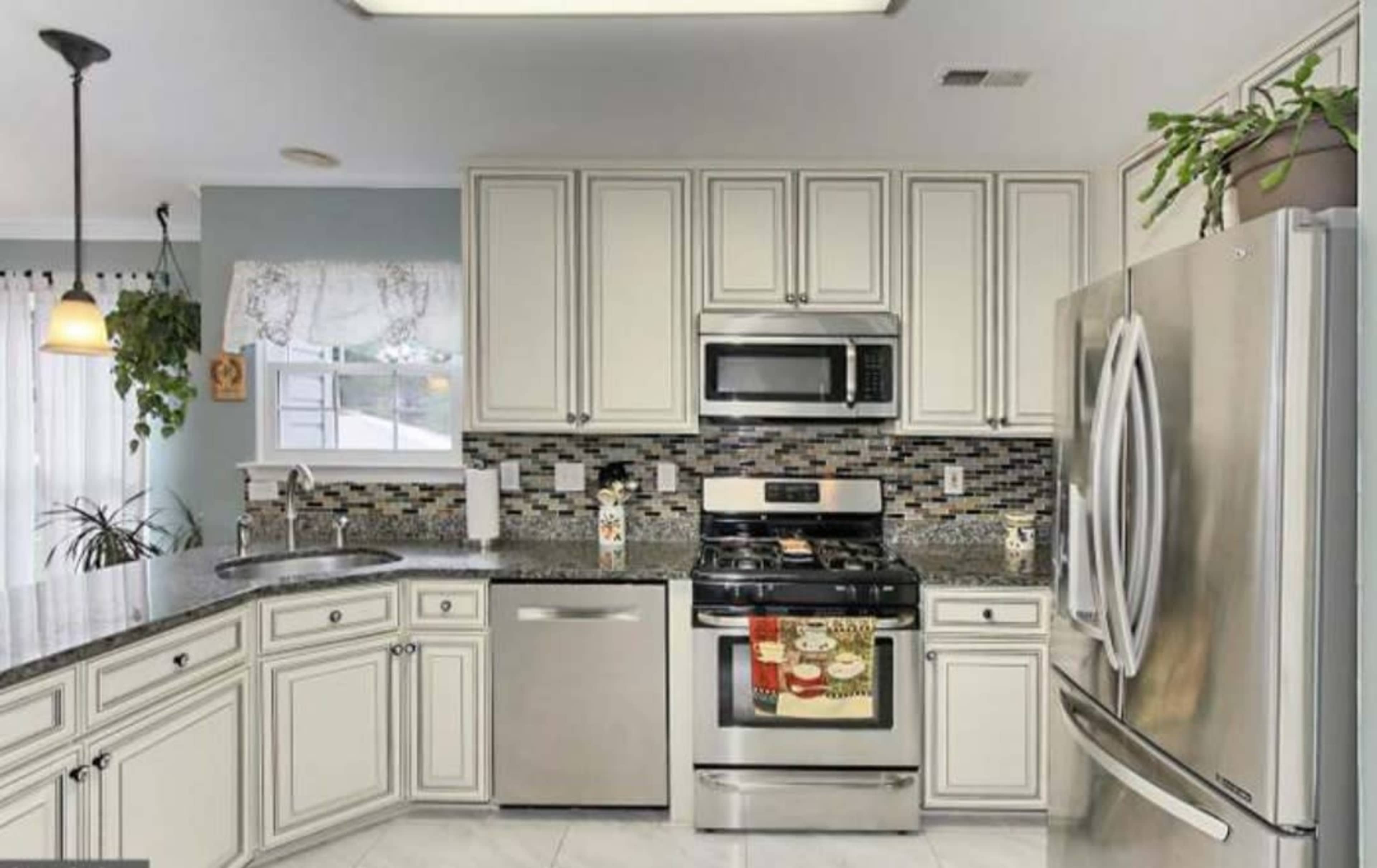 A modern kitchen with white cabinetry, stainless steel appliances, and a gray countertop.