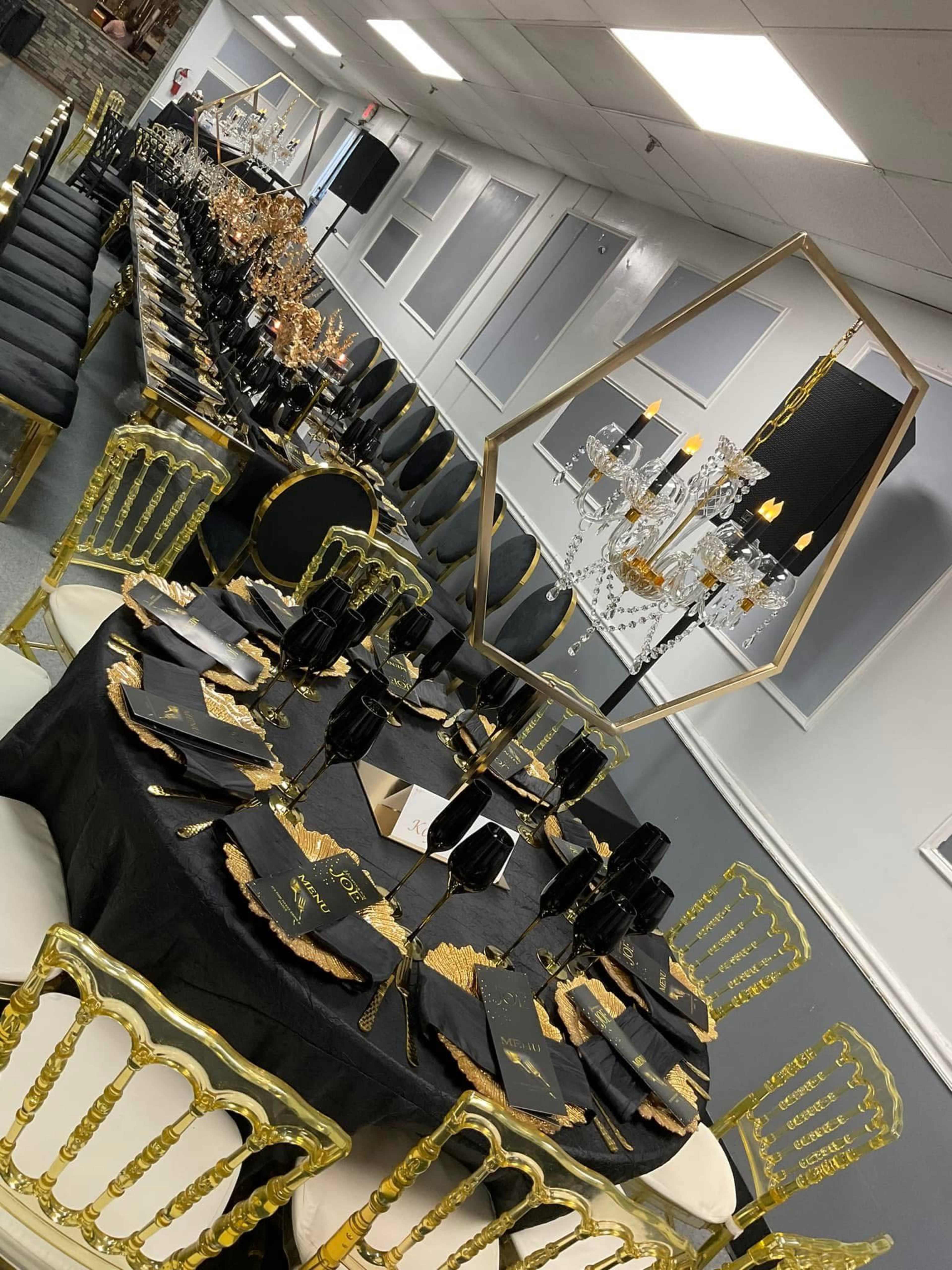 The image shows a banquet hall setup with elegantly arranged tables featuring black tablecloths, gold accents, and crystal centerpieces.