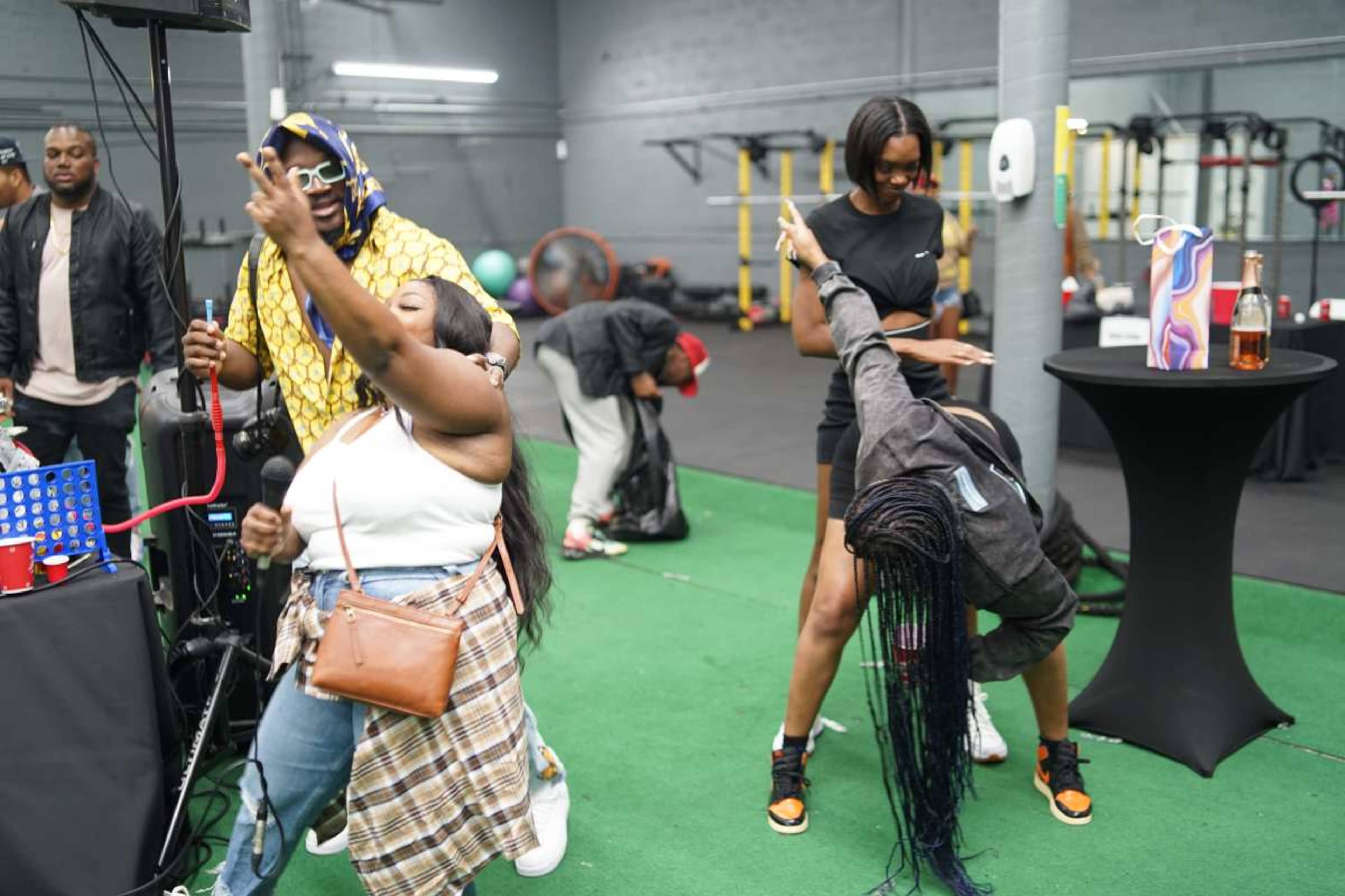 A group of people is dancing and socializing in a lively indoor gym setting.