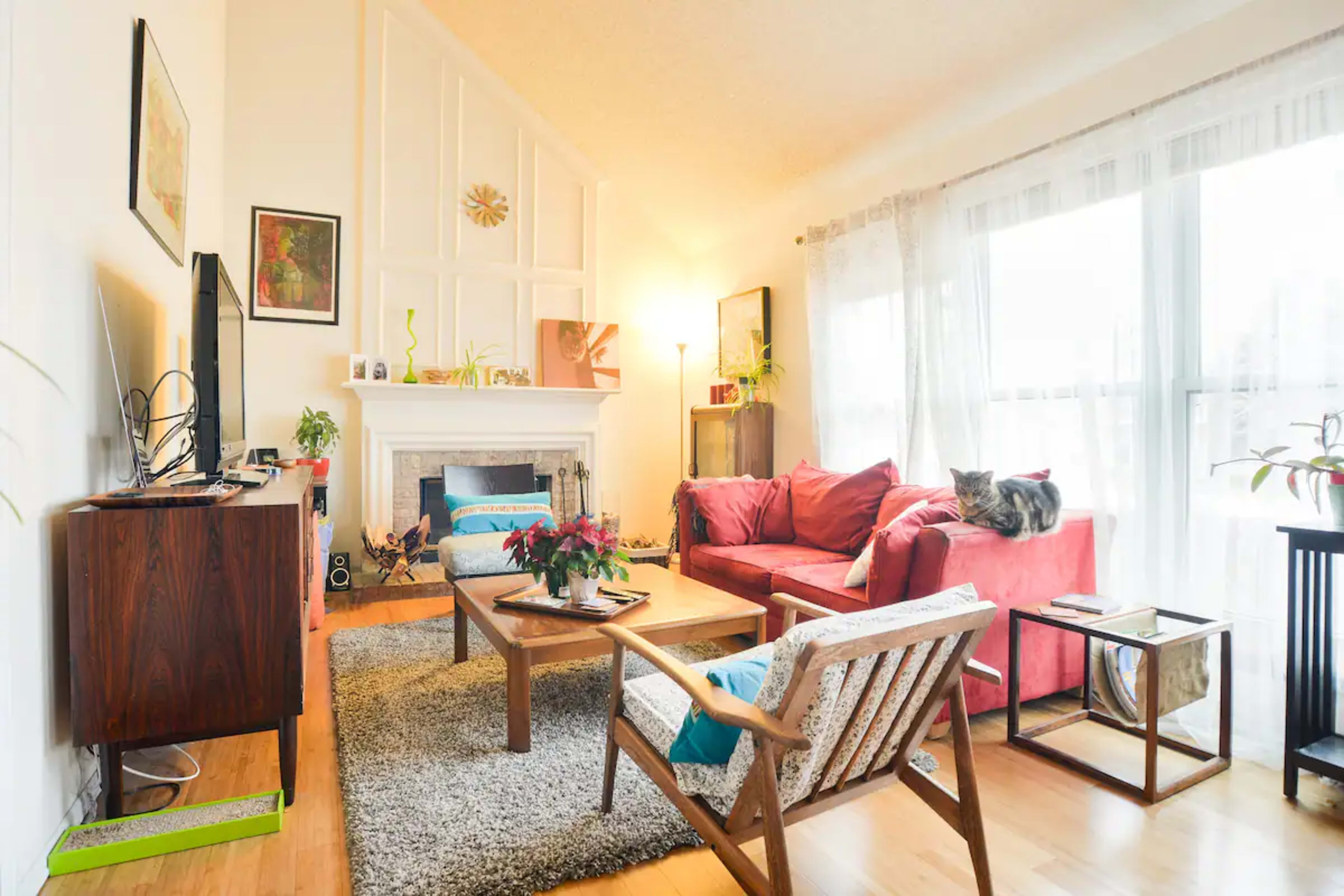 A cozy living room with a red sofa, a coffee table, and large windows that allow natural light to fill the space.