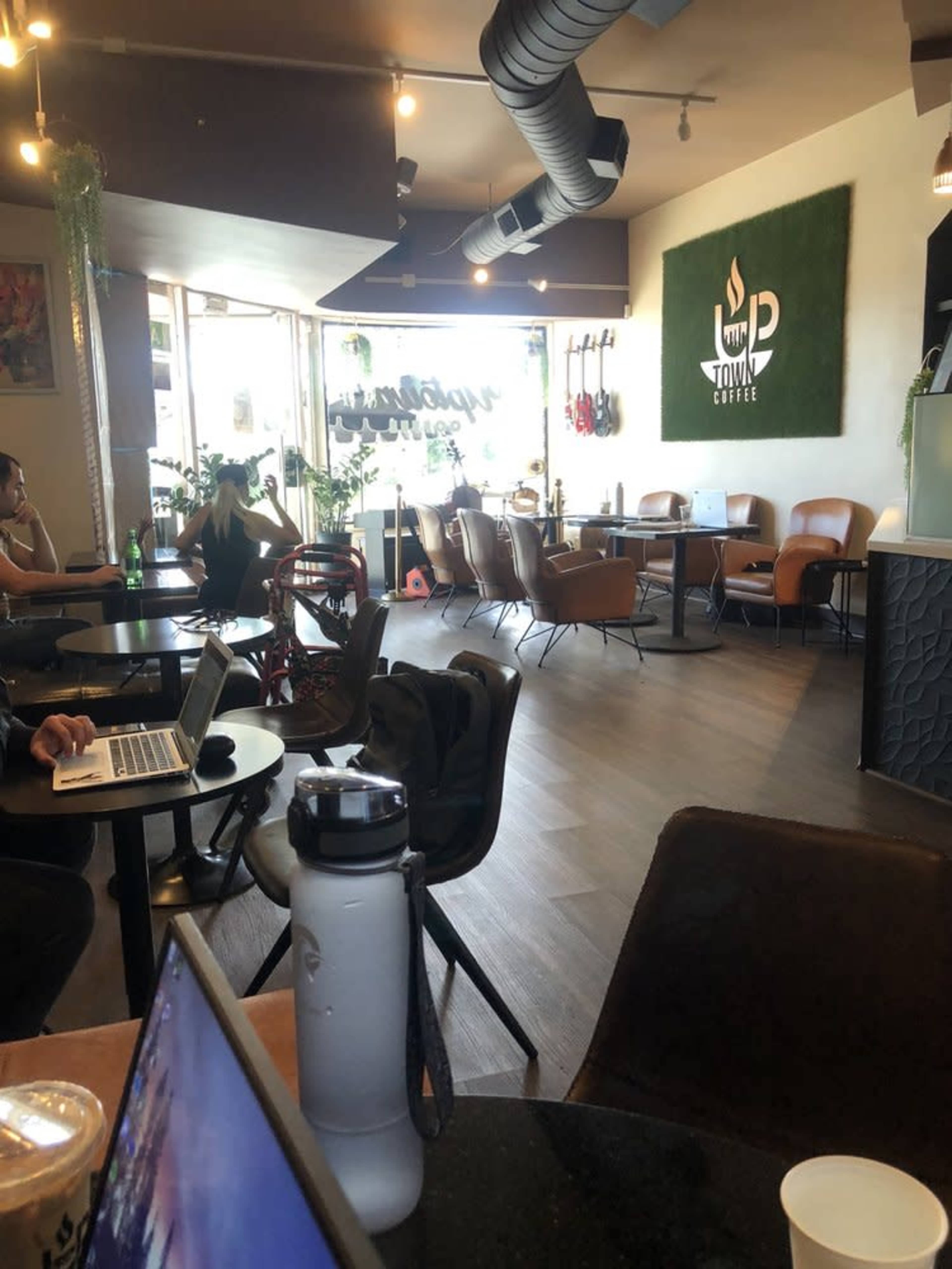 The image shows a coffee shop interior with wooden flooring, various seating options, and a bar area.