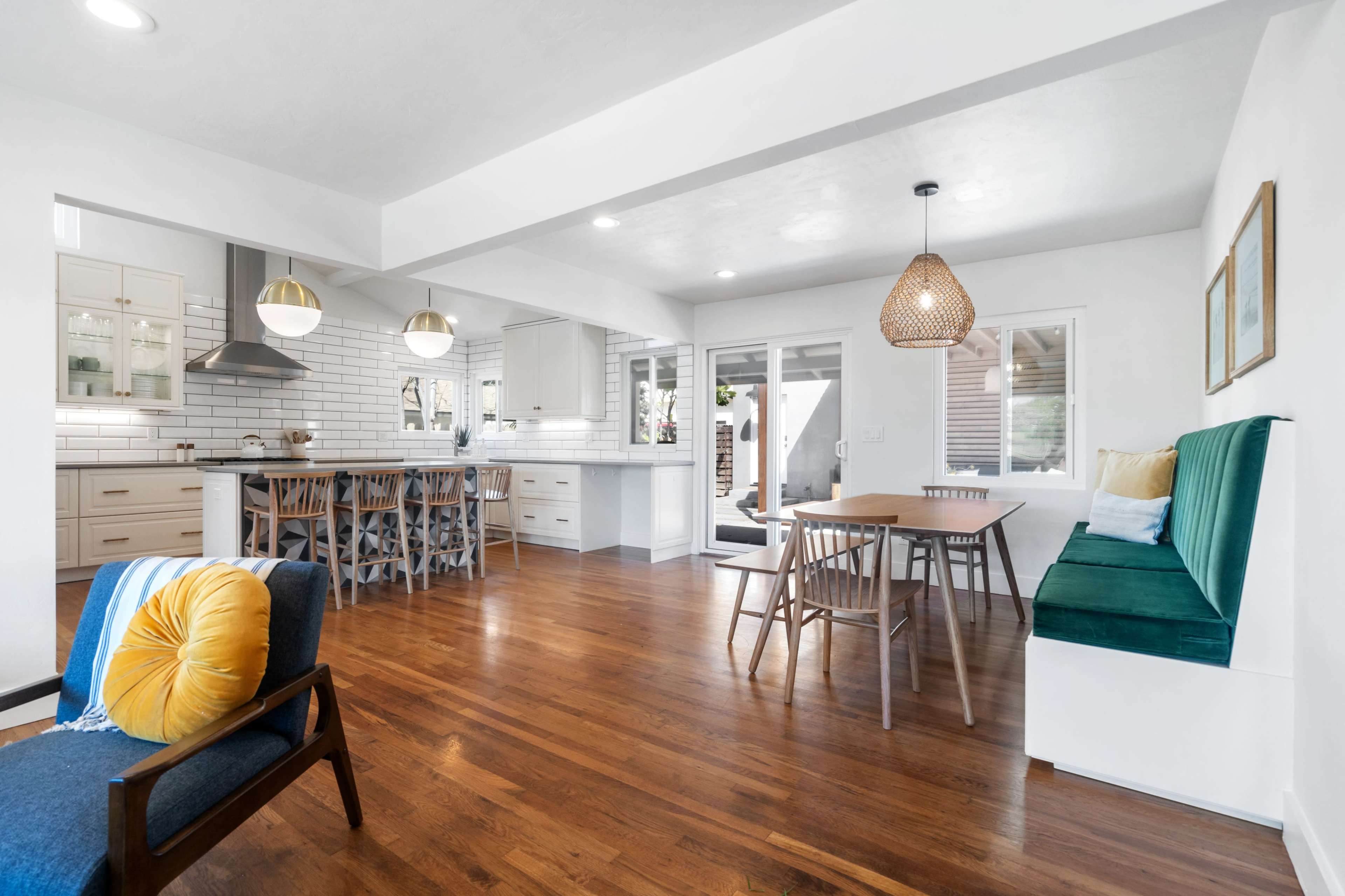 A modern kitchen and dining area featuring a large island, wooden dining table, and built-in seating along one wall.