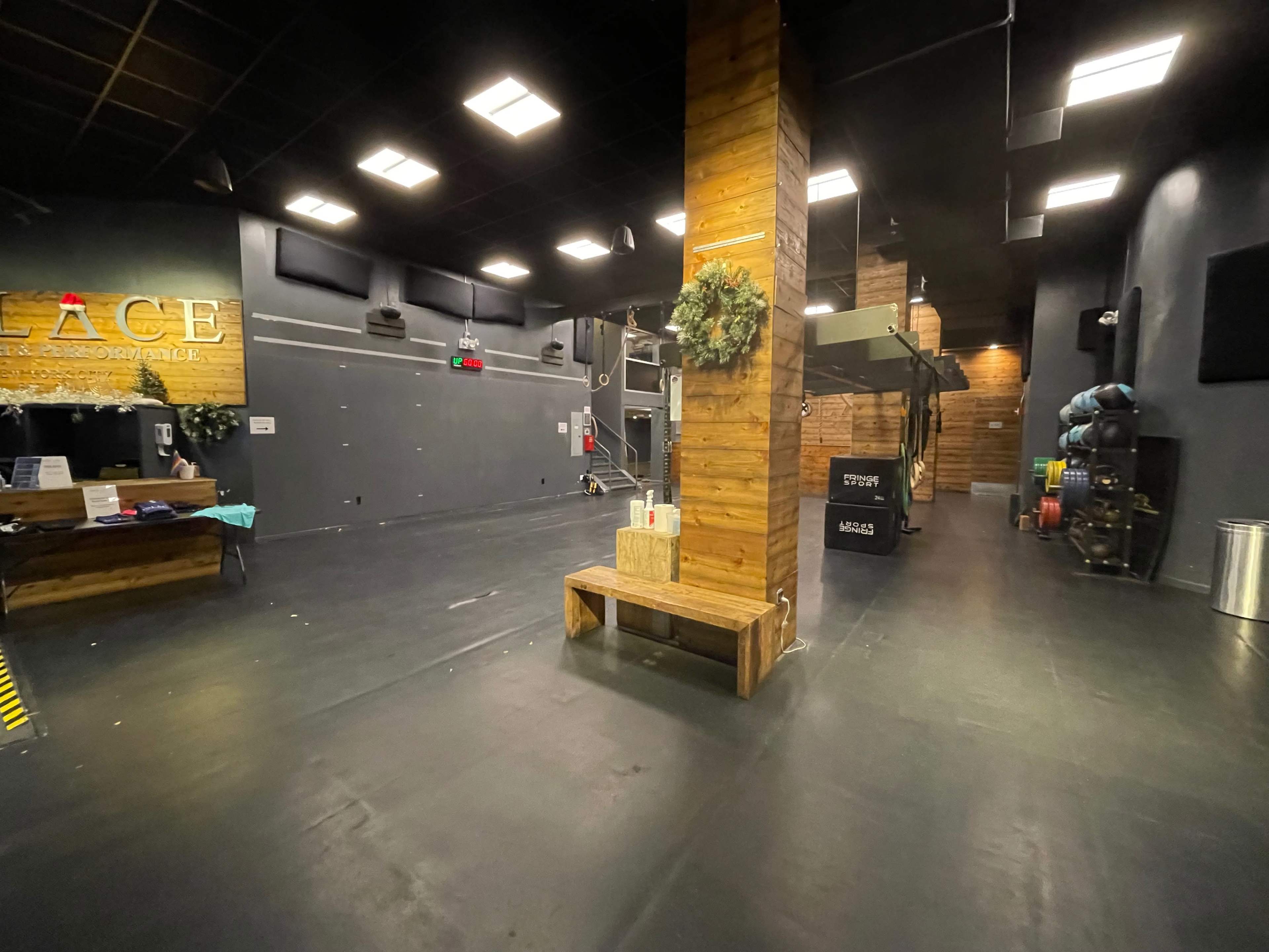 A spacious, empty gym or studio with a wooden pillar, benches, and various exercise equipment along the walls.