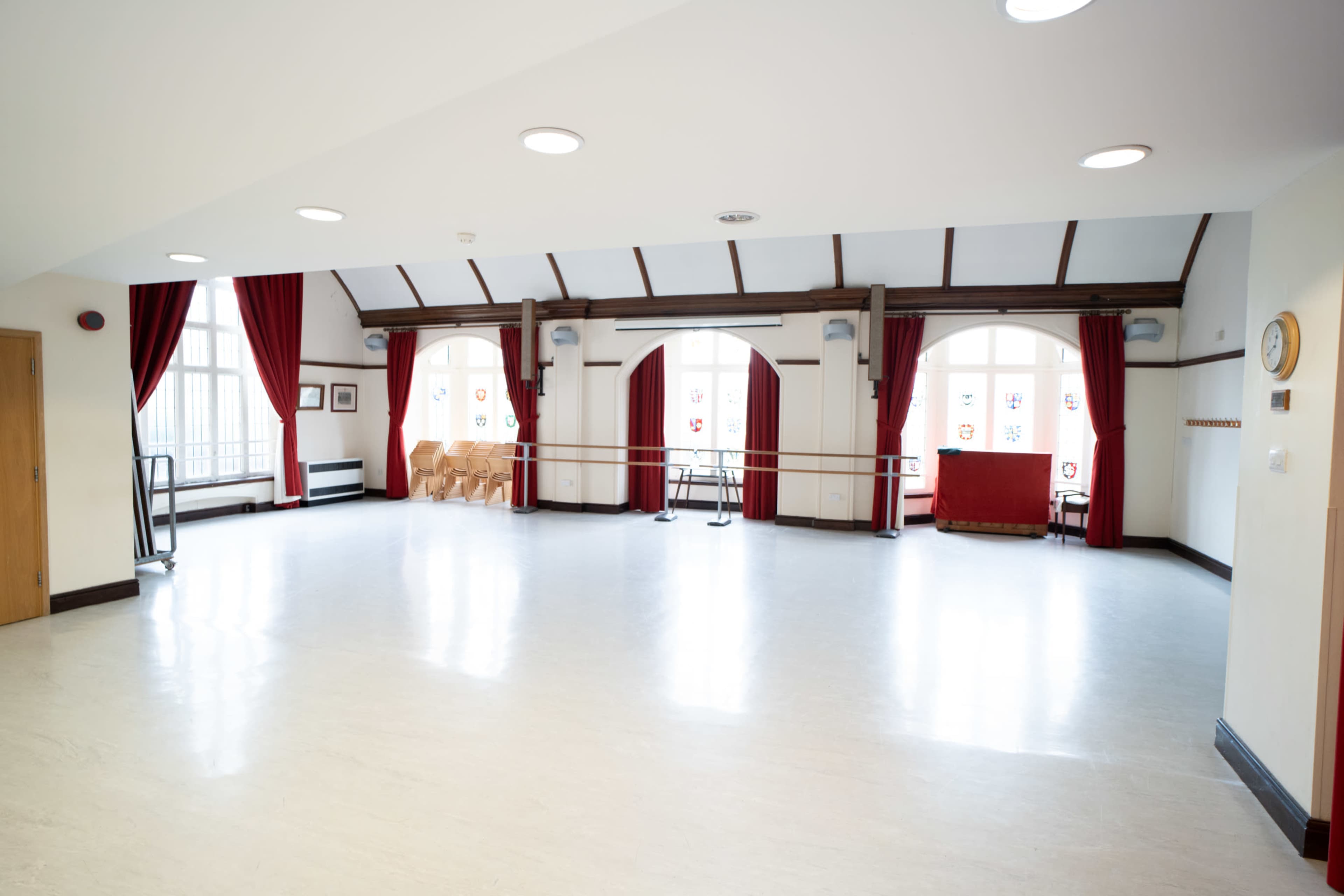 The image shows a dance studio with wooden beams, large windows, and ballet bars along the wall, illuminated by natural light.