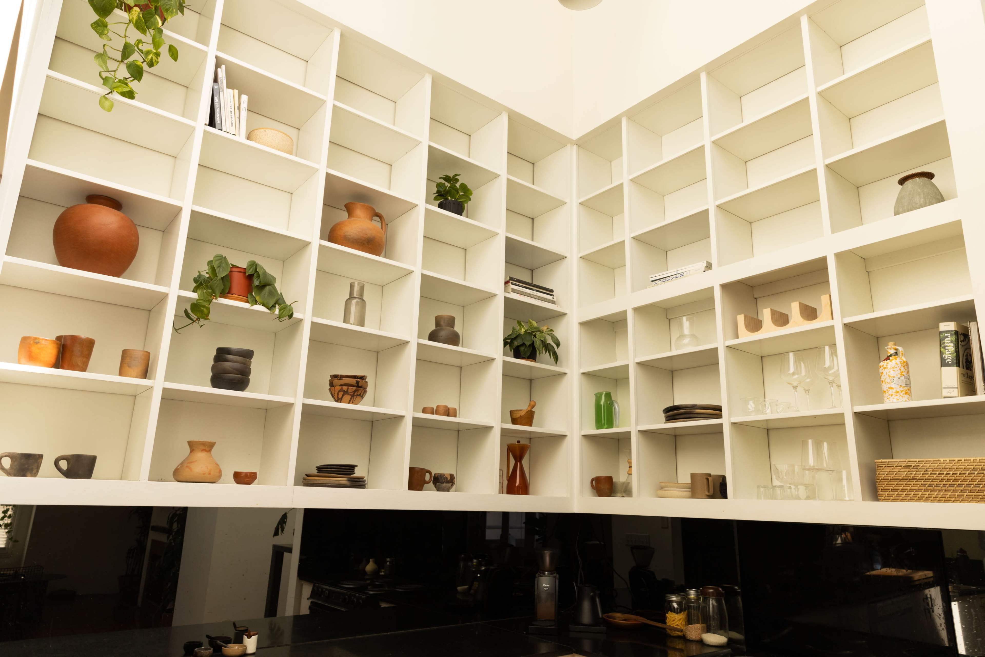 A modern, geometric shelving unit filled with various decorative items and plants.