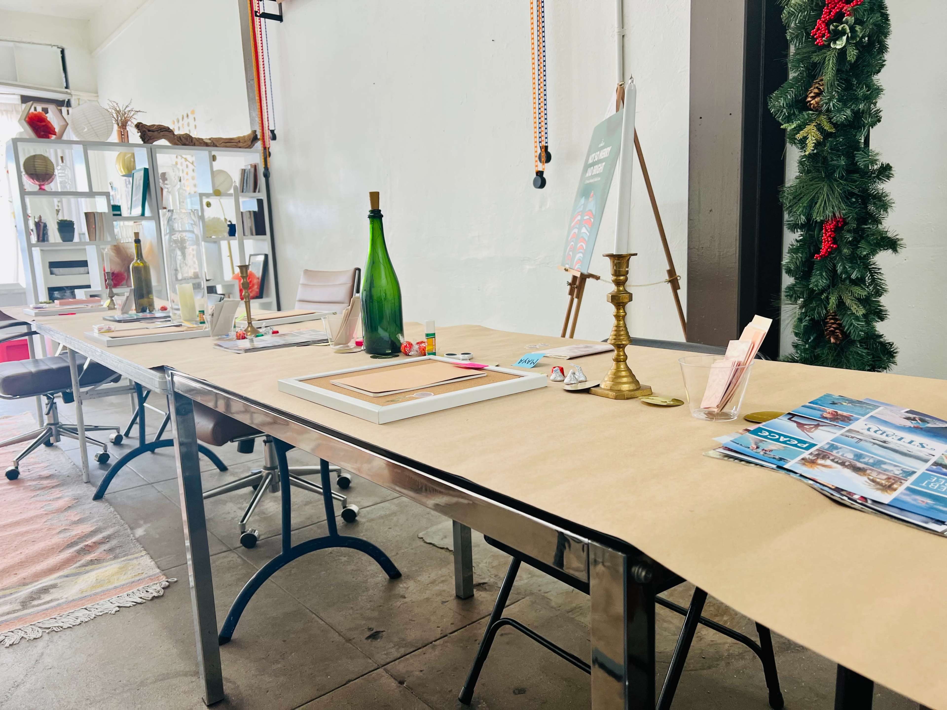 A long table is set with a variety of decorative items, including a green bottle, a candlestick, and magazines, all arranged on a brown paper covering.