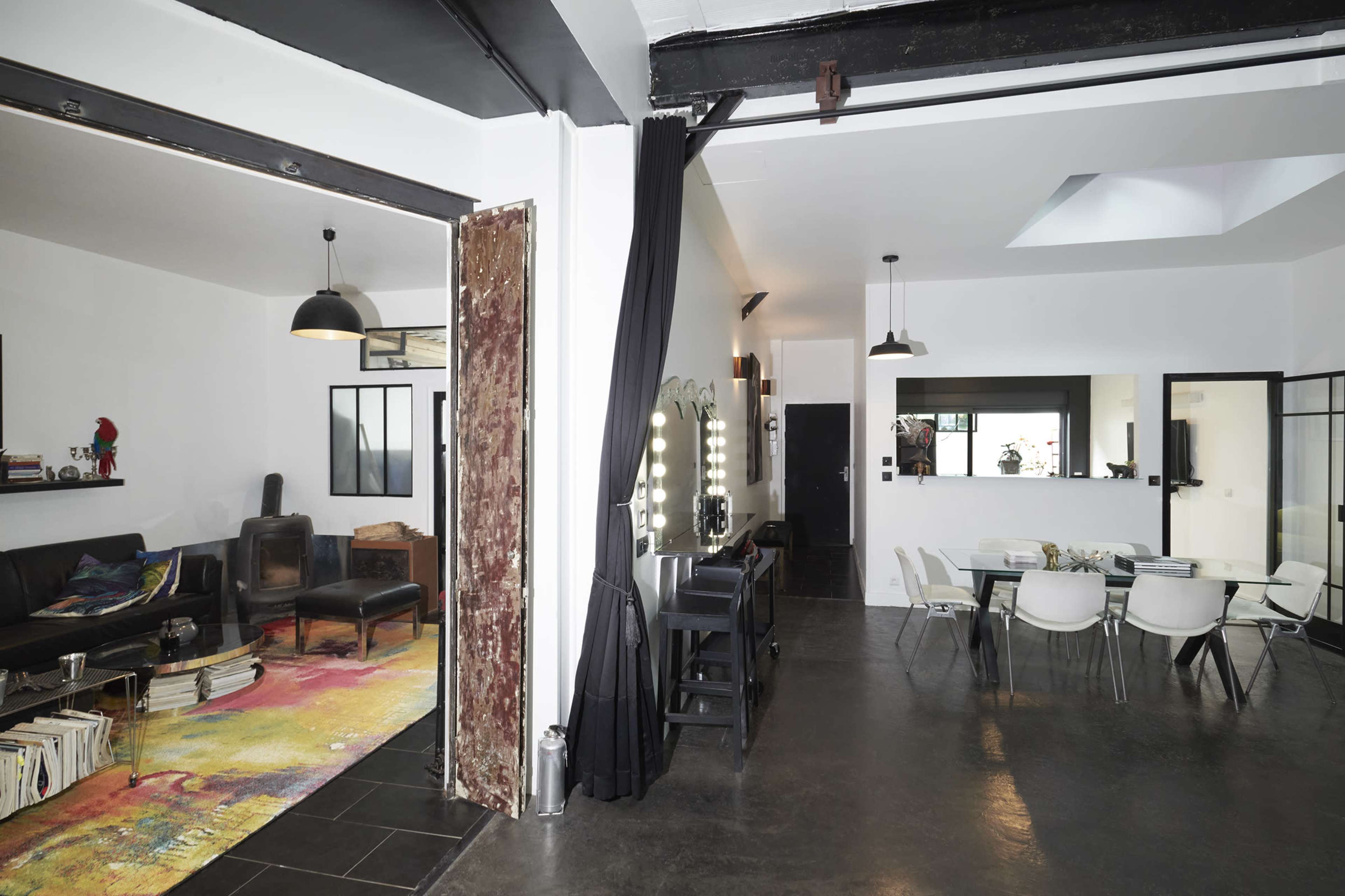 A modern, open-concept living space divided between a cozy lounge area and a dining area with a sleek table and chairs.