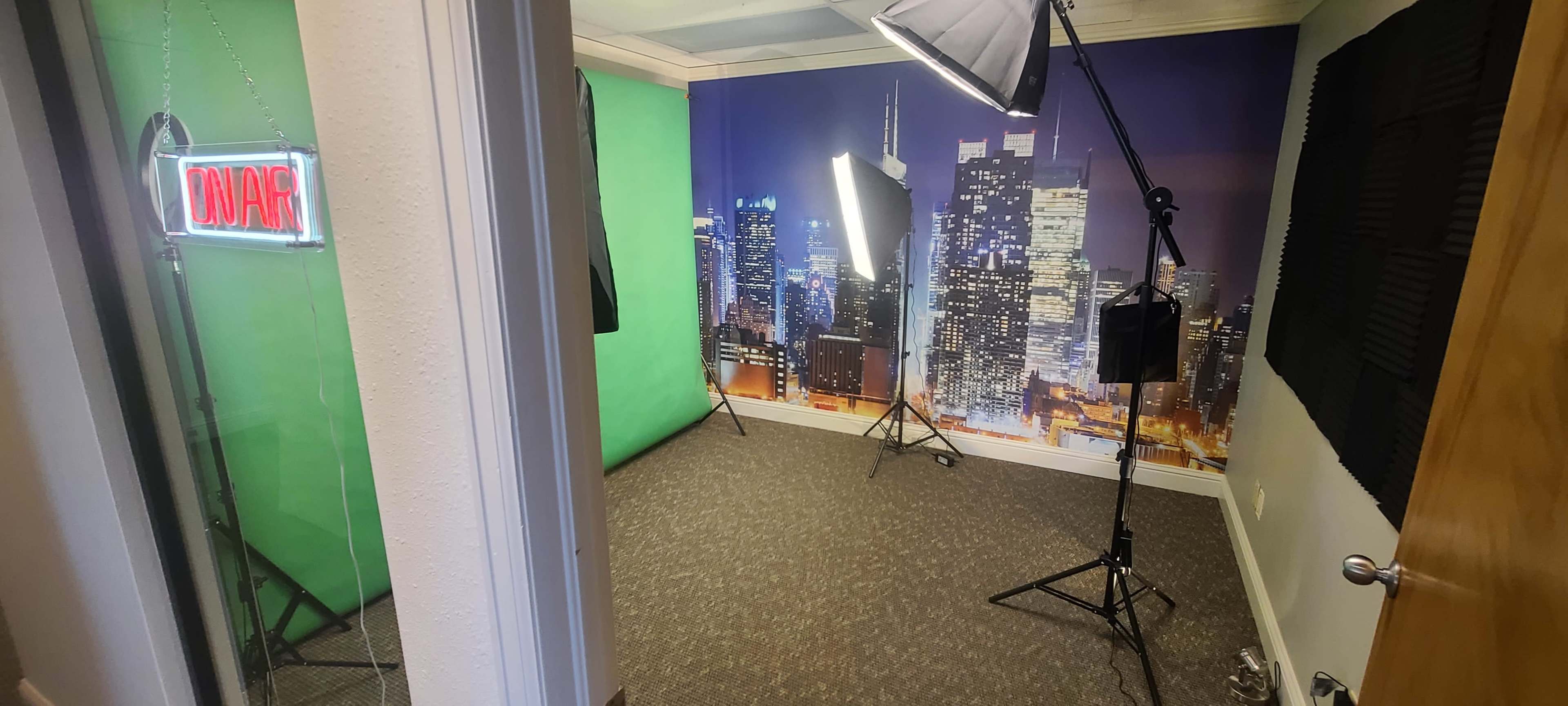 A studio setup featuring a green screen, softbox lights, and a city skyline backdrop.