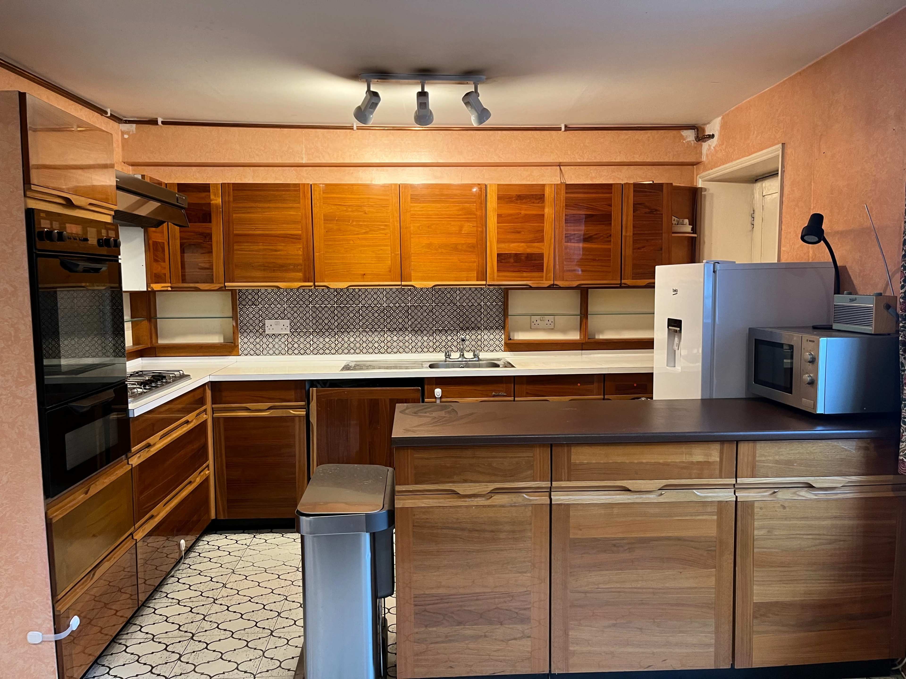A kitchen featuring wooden cabinetry, a central island, and a combination of modern appliances, including an oven and refrigerator.