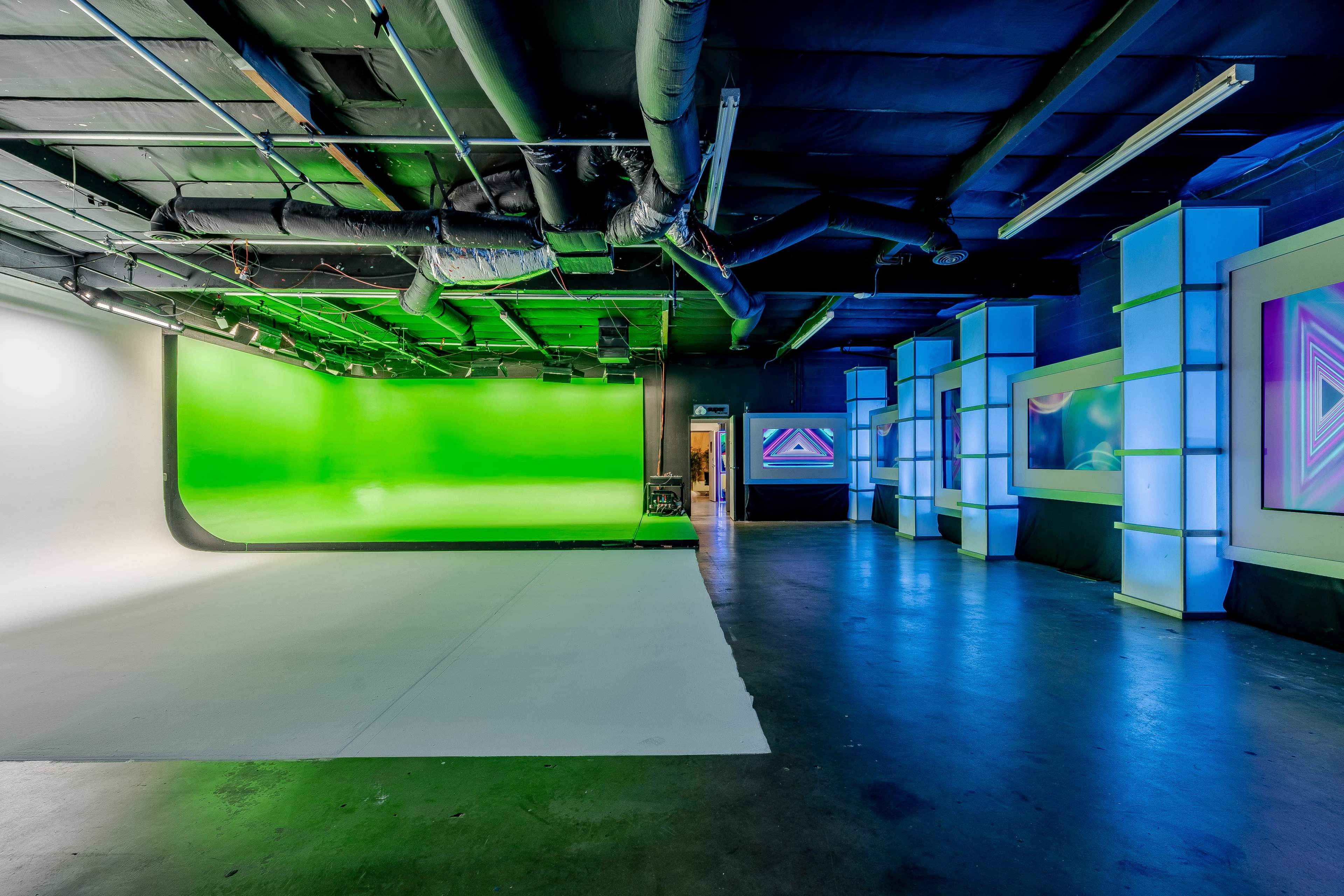 A studio space featuring a green screen area on one side and brightly lit, geometric displays on the other.