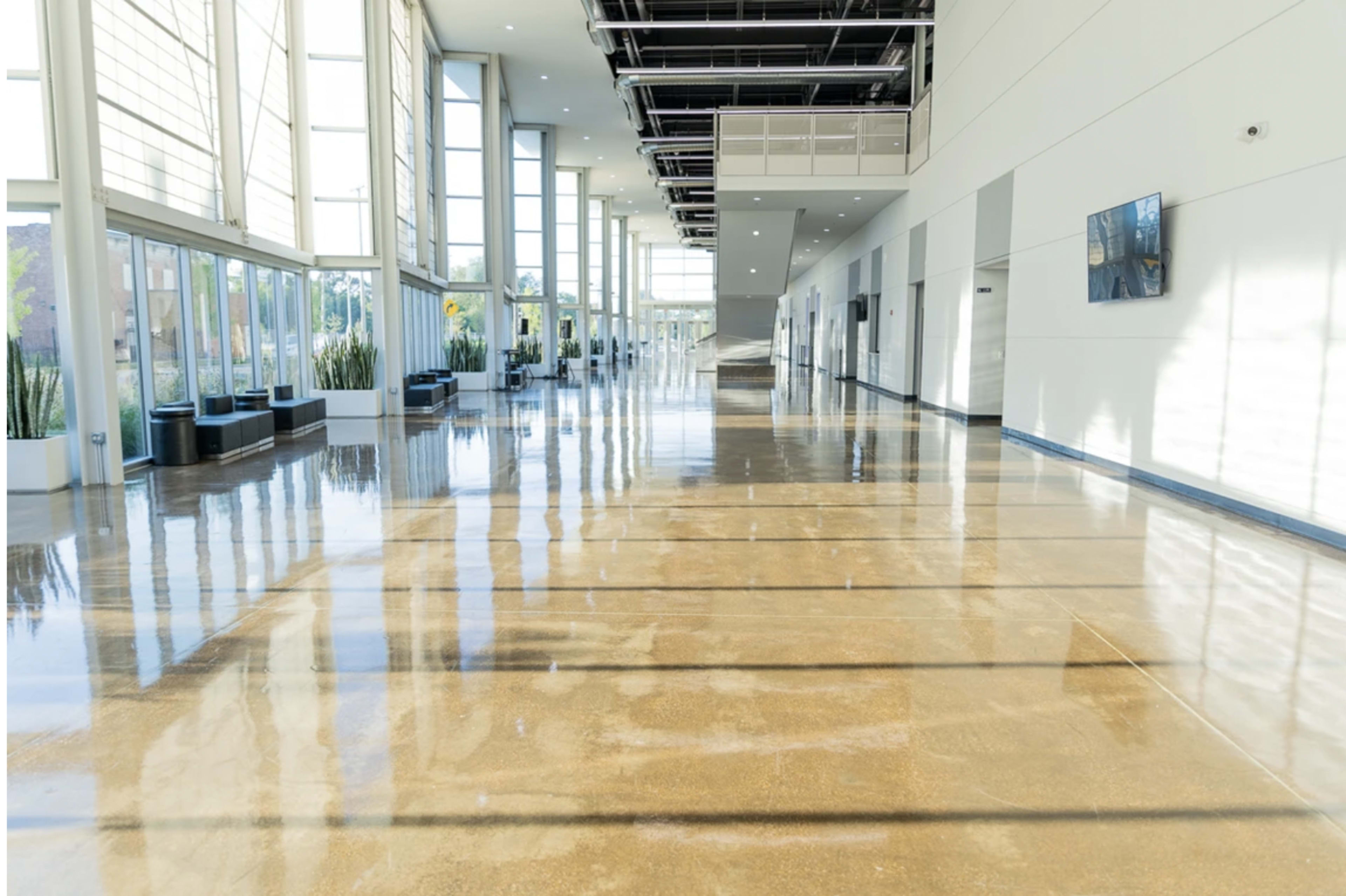 A spacious, brightly lit corridor with polished floors and large windows along one side.