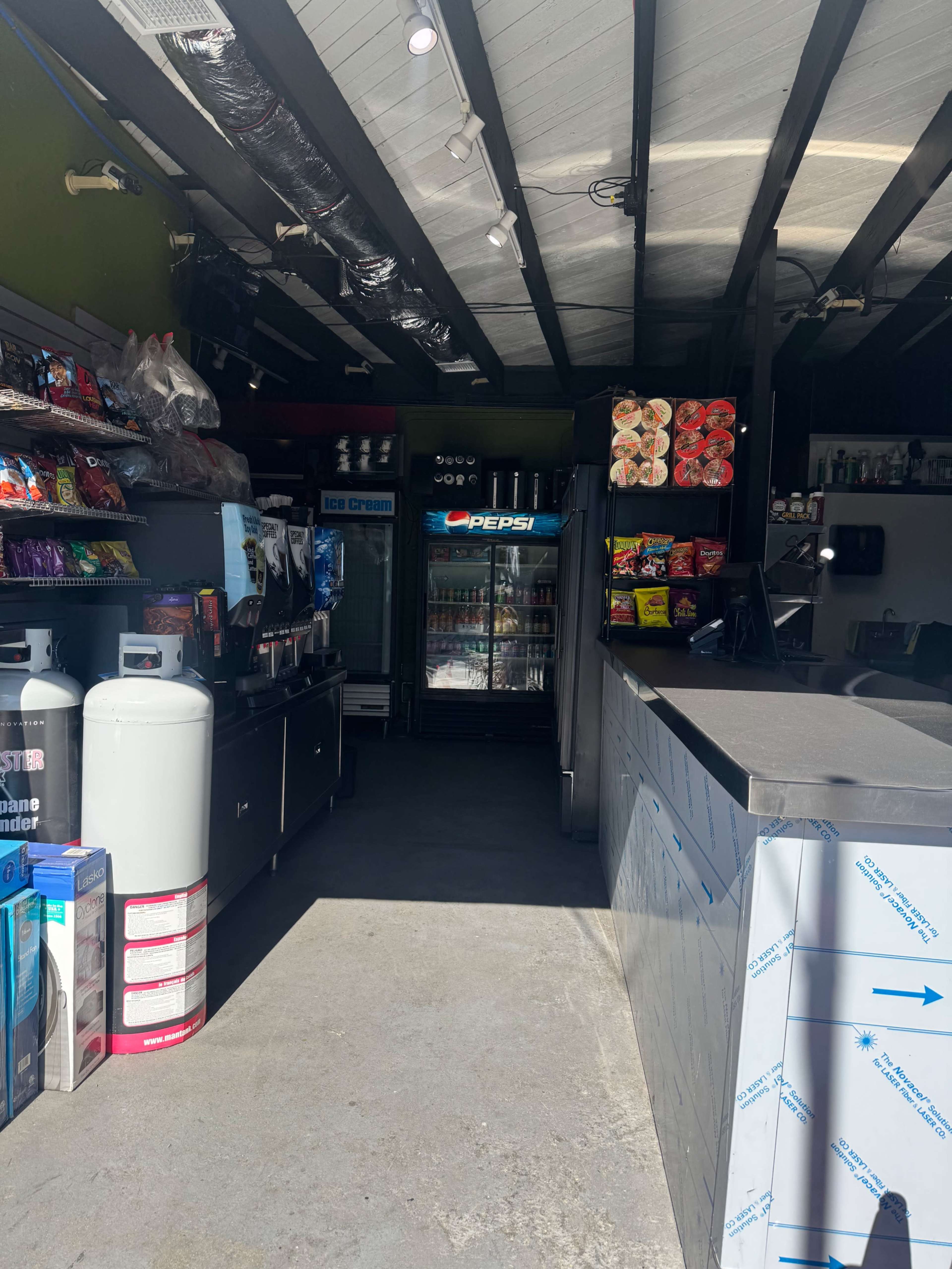 The image shows the interior of a convenience store with shelves stocked with snacks and beverages, including a Pepsi refrigerator in the background.