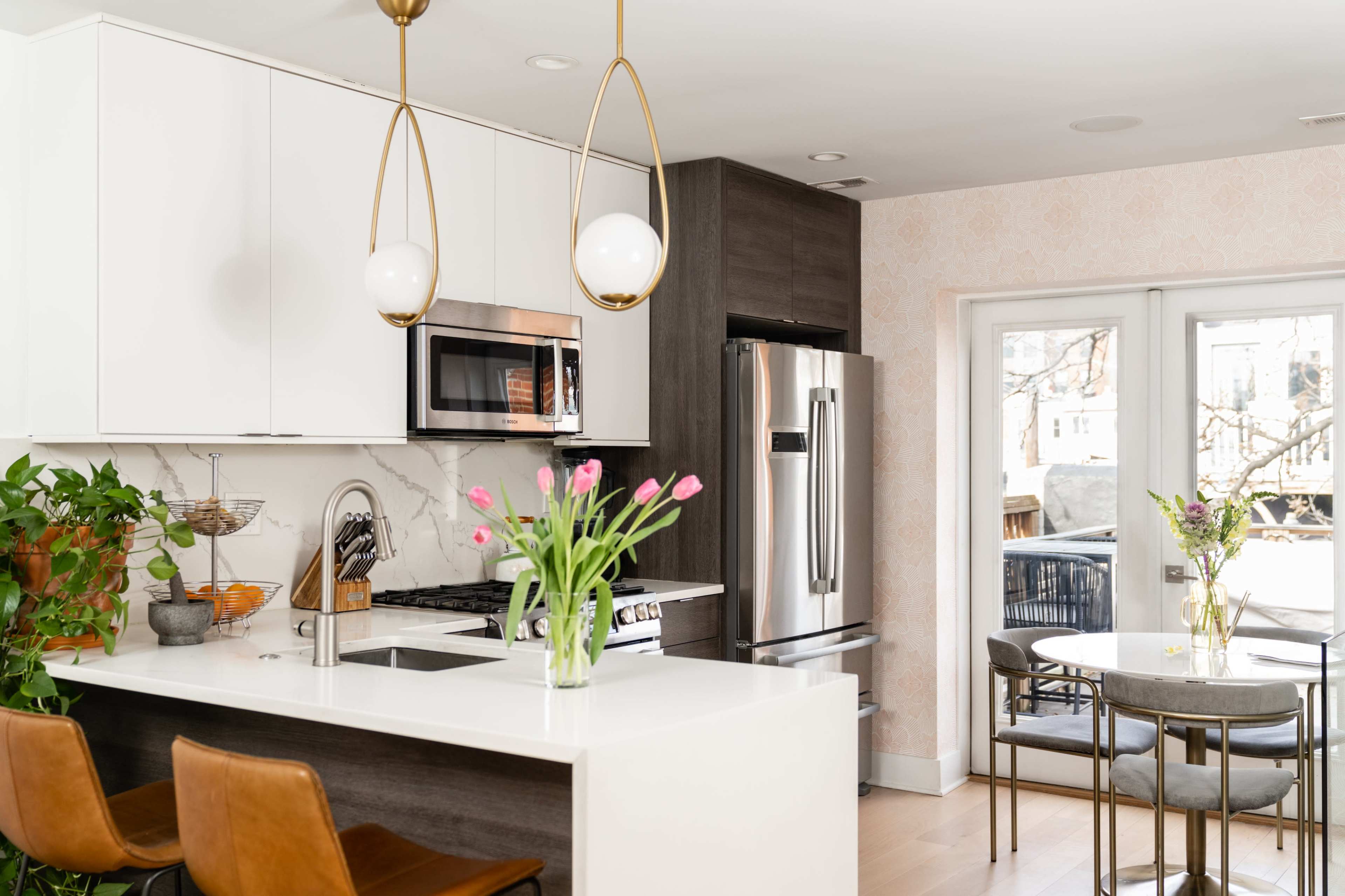 A modern kitchen features white cabinetry, stainless steel appliances, and a dining area with a round table and chairs.