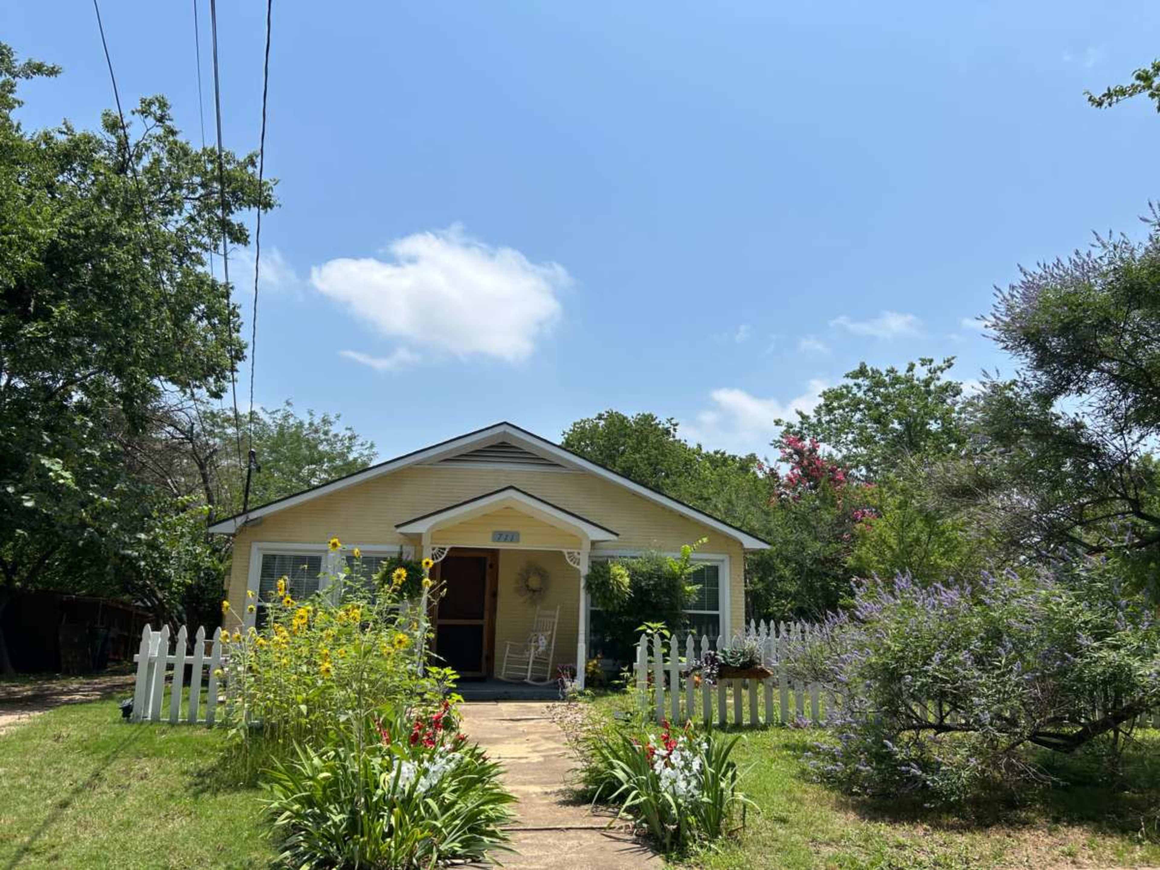 Bathed in light, modern meets historic 1940 Doctors Bungalo with covered poarch over looking  sweeping backyard and rustic cozy garden. Image in McKinney, Mckinney, TX