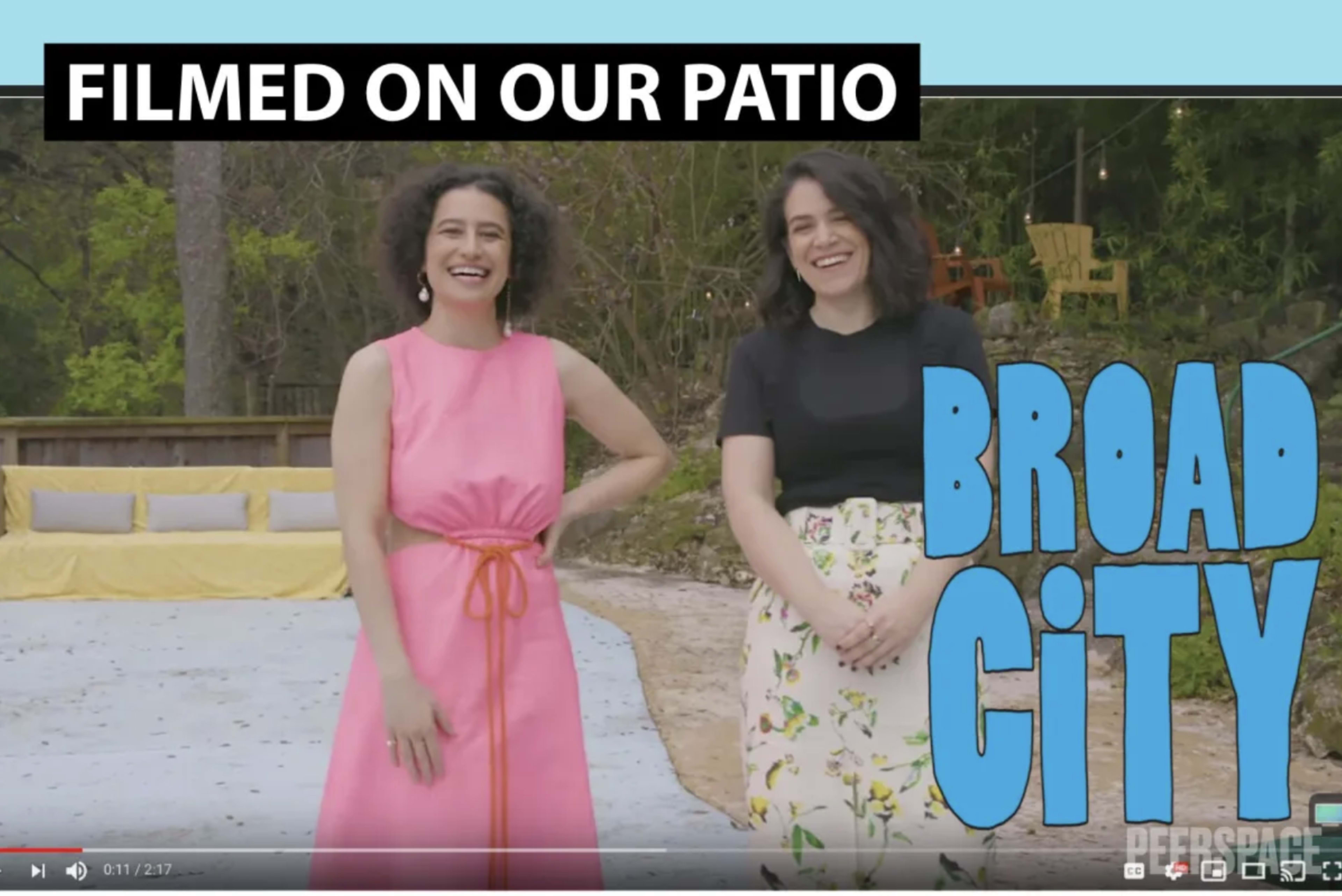 Two women stand on a patio, smiling and wearing colorful outfits, with the text "FILMED ON OUR PATIO" and "BROAD CITY" displayed.