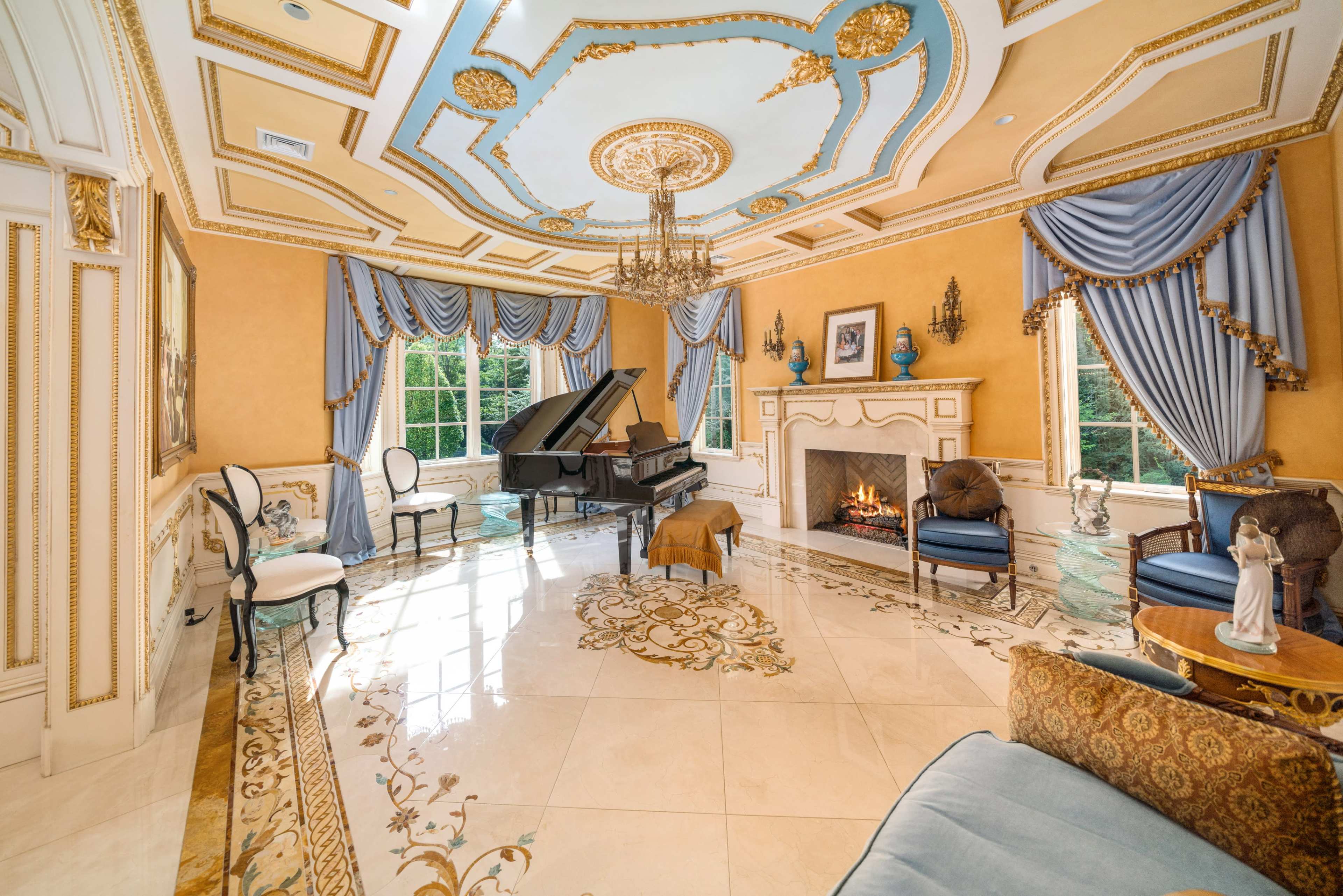 An opulent room featuring a grand piano, a fireplace, and elaborate ceiling details, with ornate furnishings and draped windows.