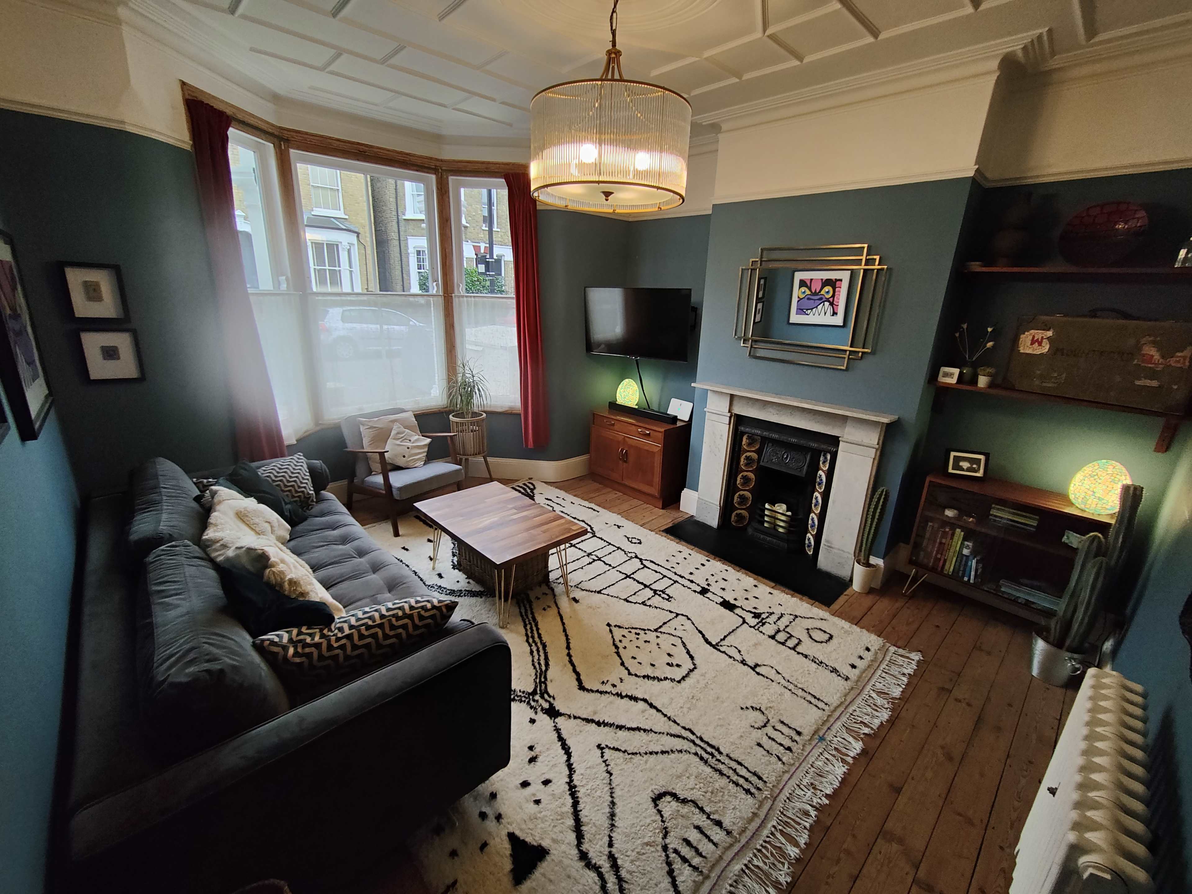 A stylish living room featuring a gray sofa, a wooden coffee table, a vintage fireplace, and a television mounted on the wall.