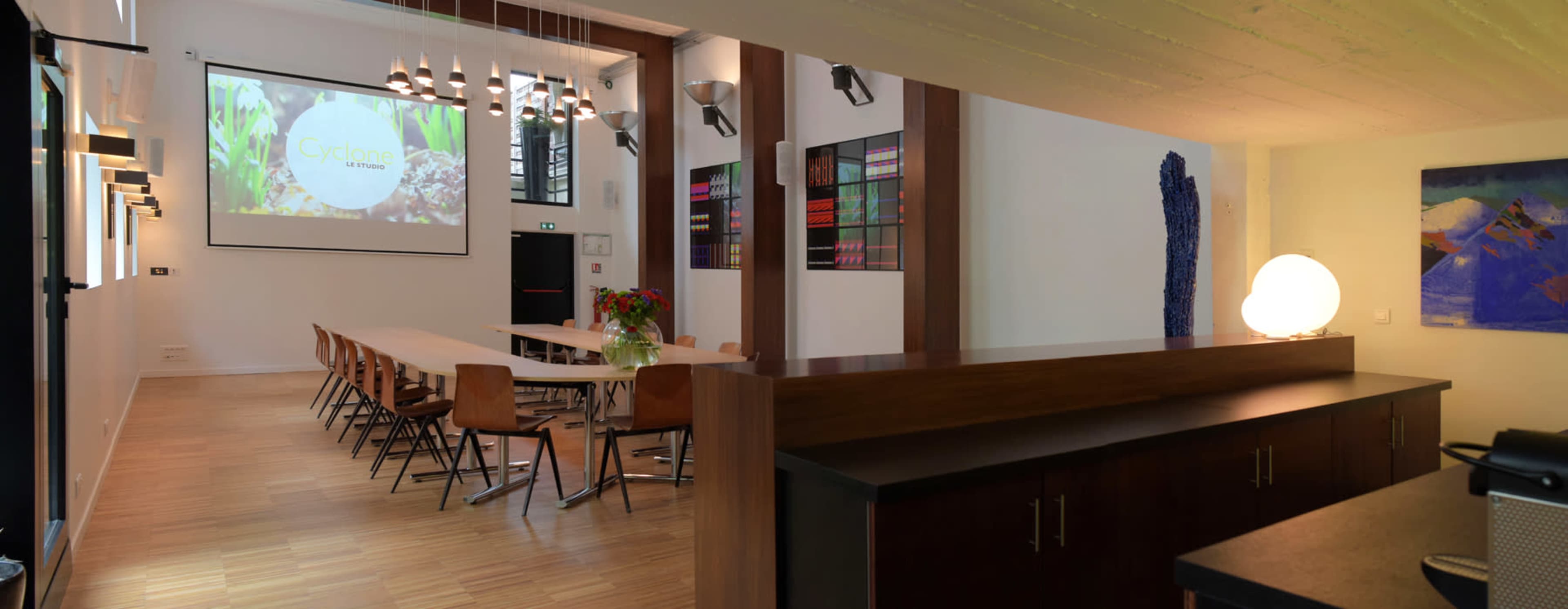 A modern meeting room with a long table, chairs, and a projector screen displaying "Ciclope" on one wall.