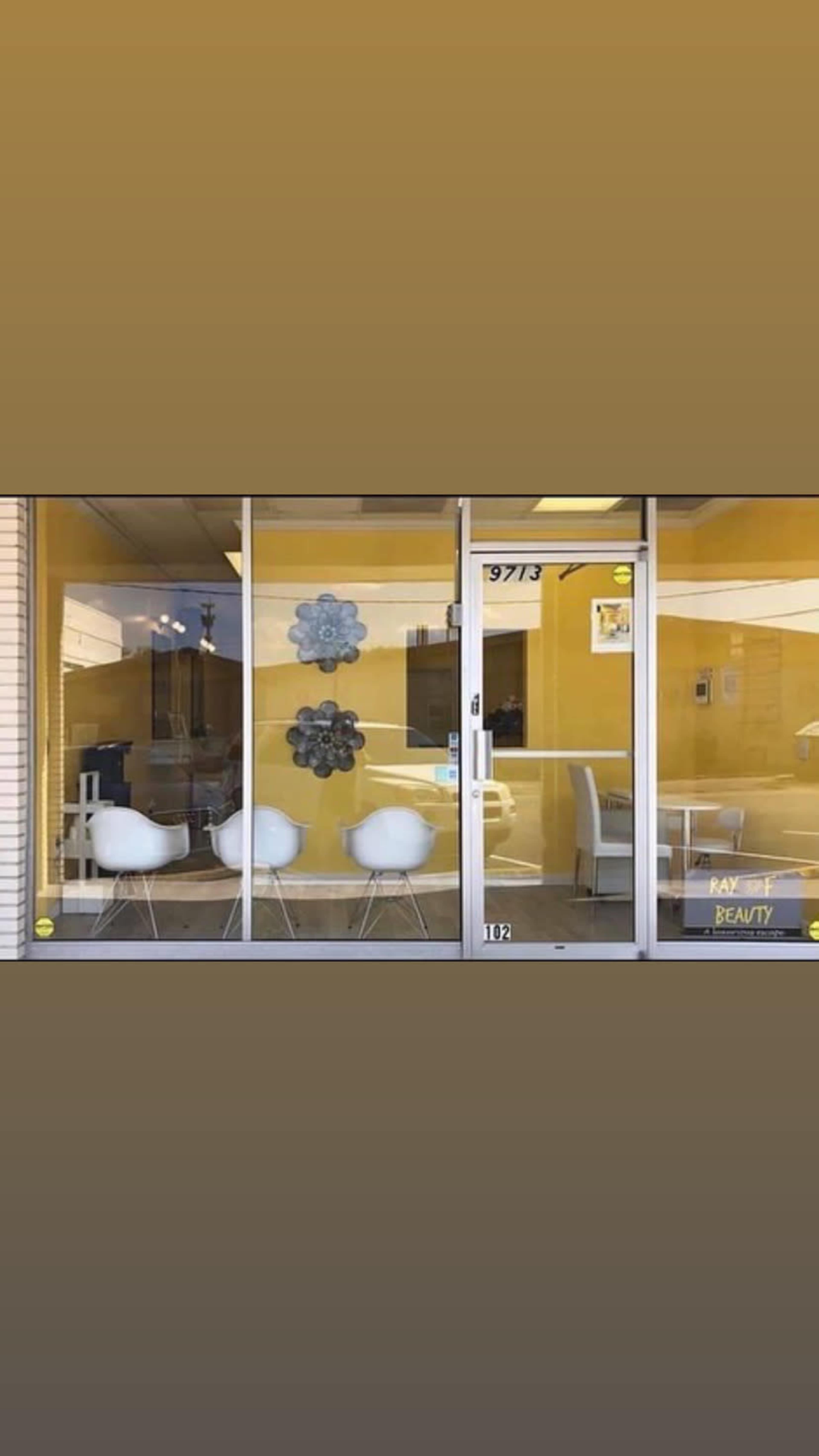 The storefront features large glass windows with three white chairs and yellow walls, displaying the name "Ray Beauty" near the entrance.