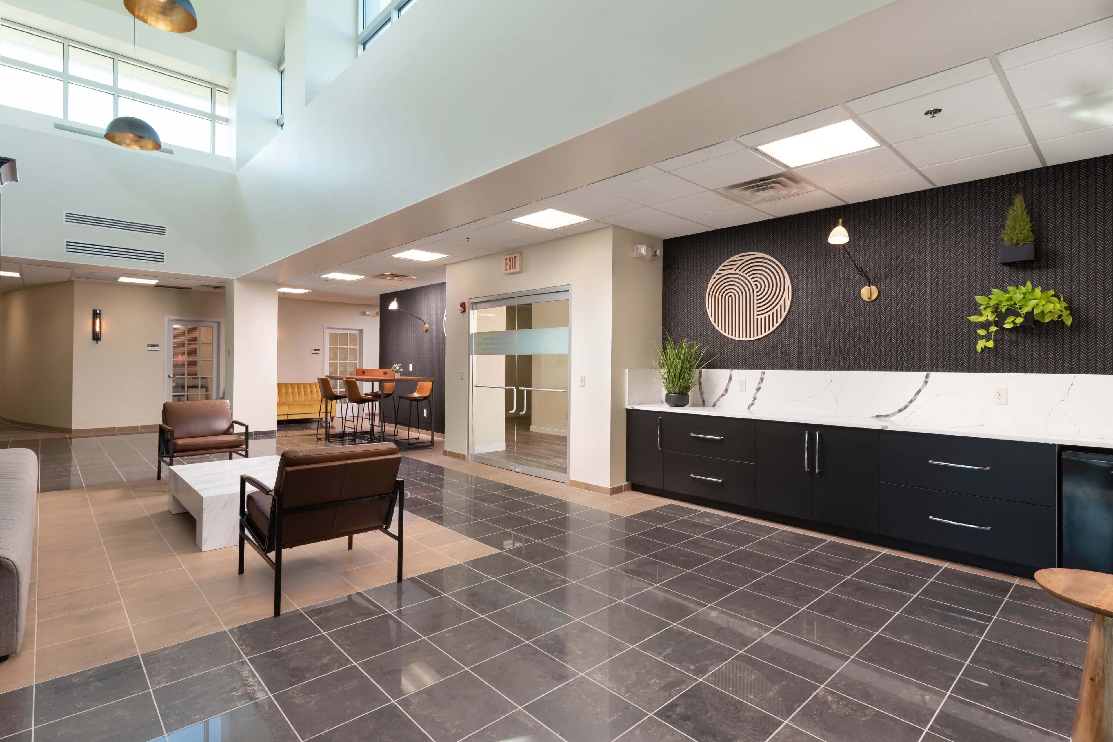 A modern lobby area featuring tiled flooring, contemporary furniture, and a reception area with a textured wall design.