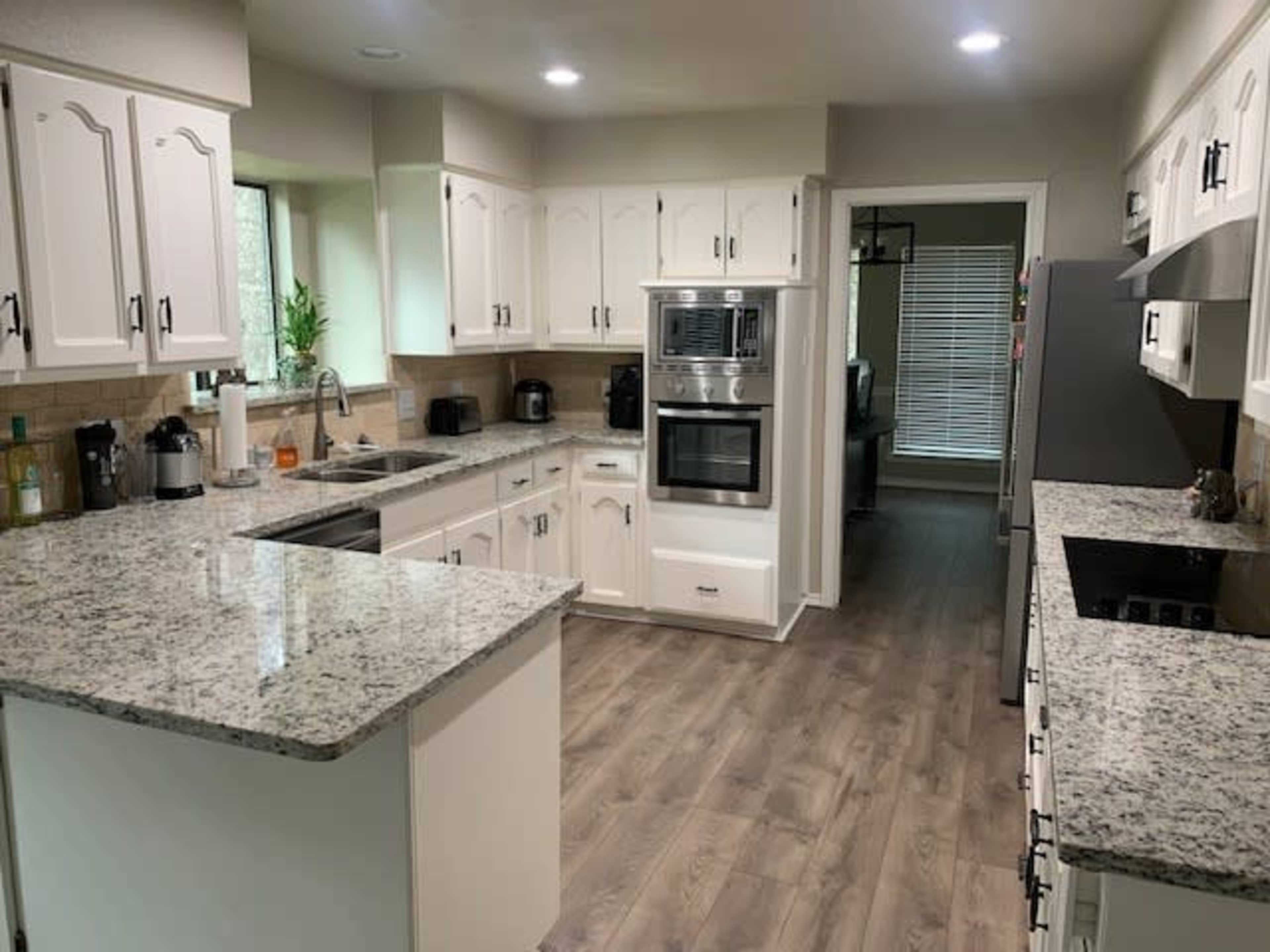 A modern kitchen features white cabinets, a granite countertop, and stainless steel appliances.
