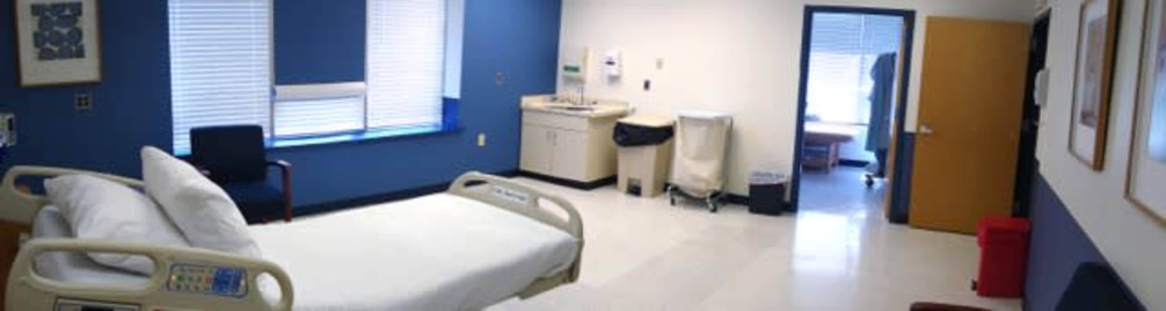 A hospital room with a bed, medical equipment, and a window, featuring a clean and organized layout.