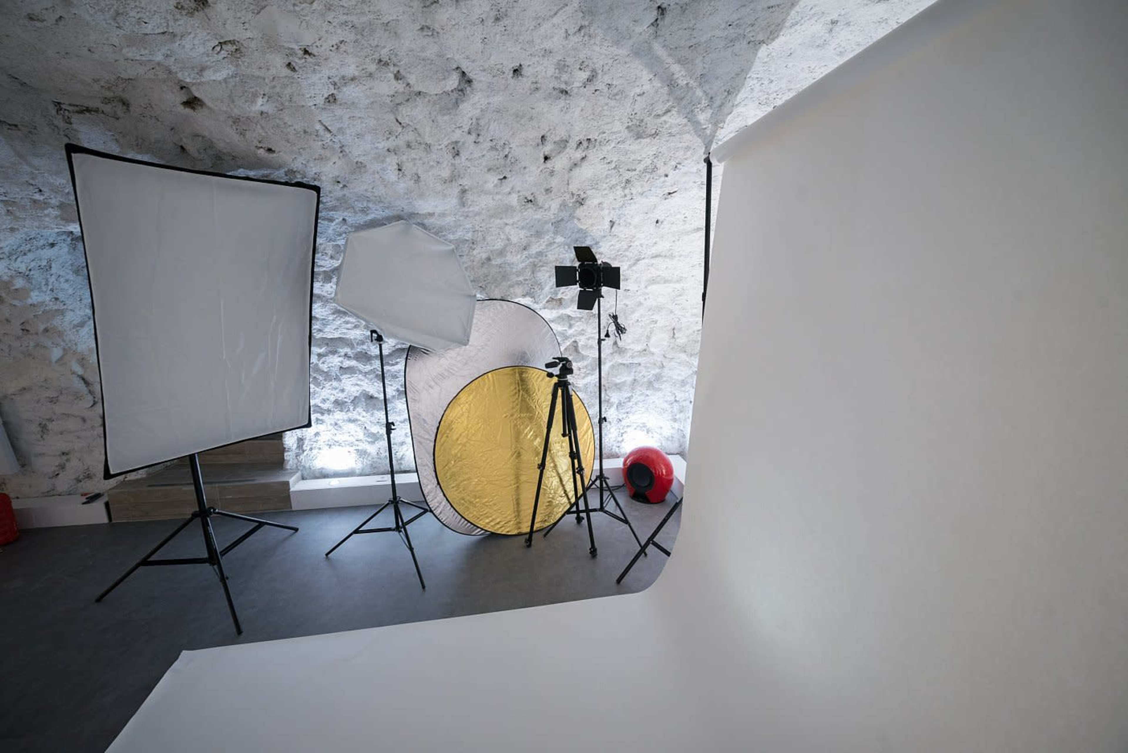 A photography studio setup with multiple light modifiers and a blank backdrop.