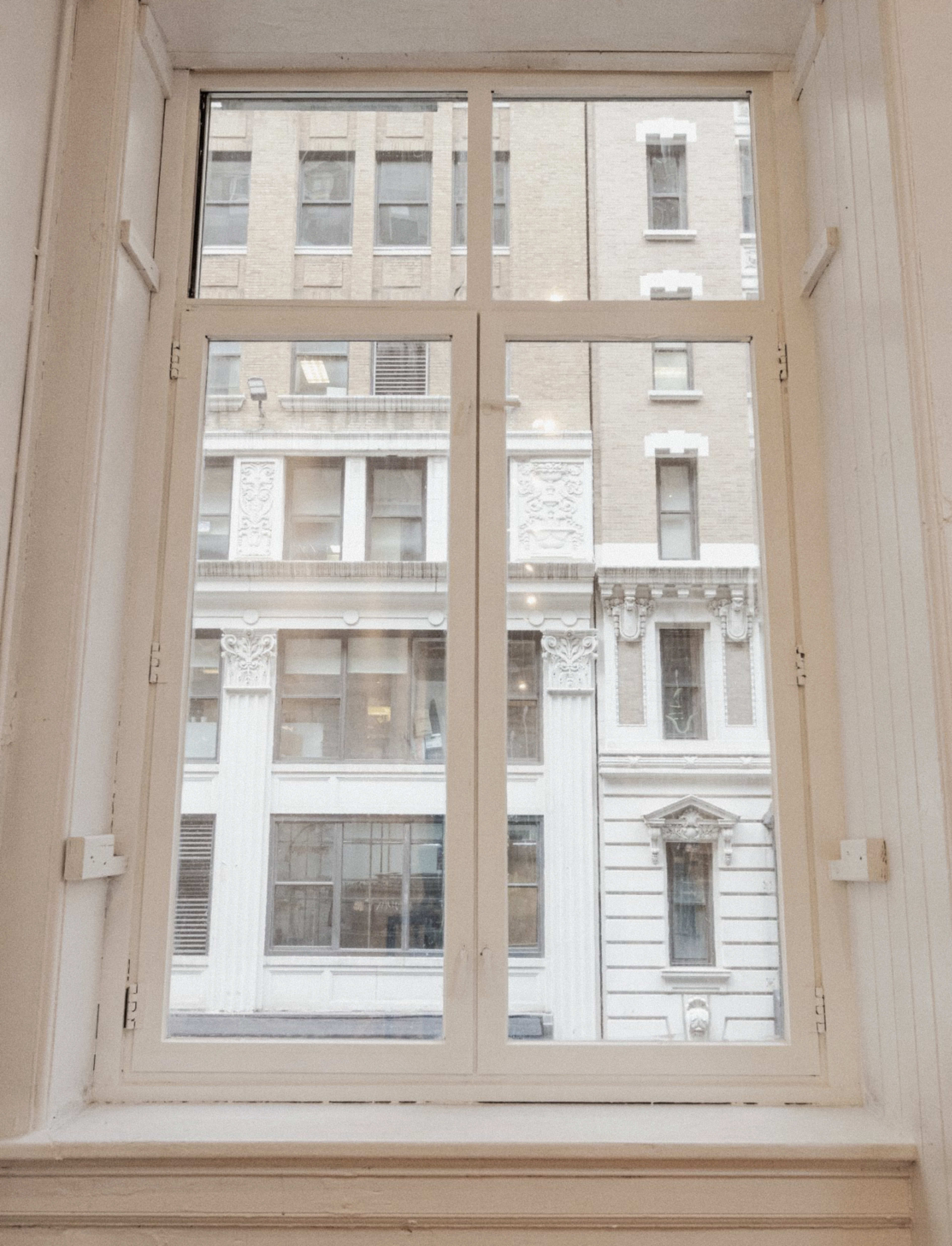 A white-framed window displays the exterior of a building with decorative columns and a façade featuring multiple windows.
