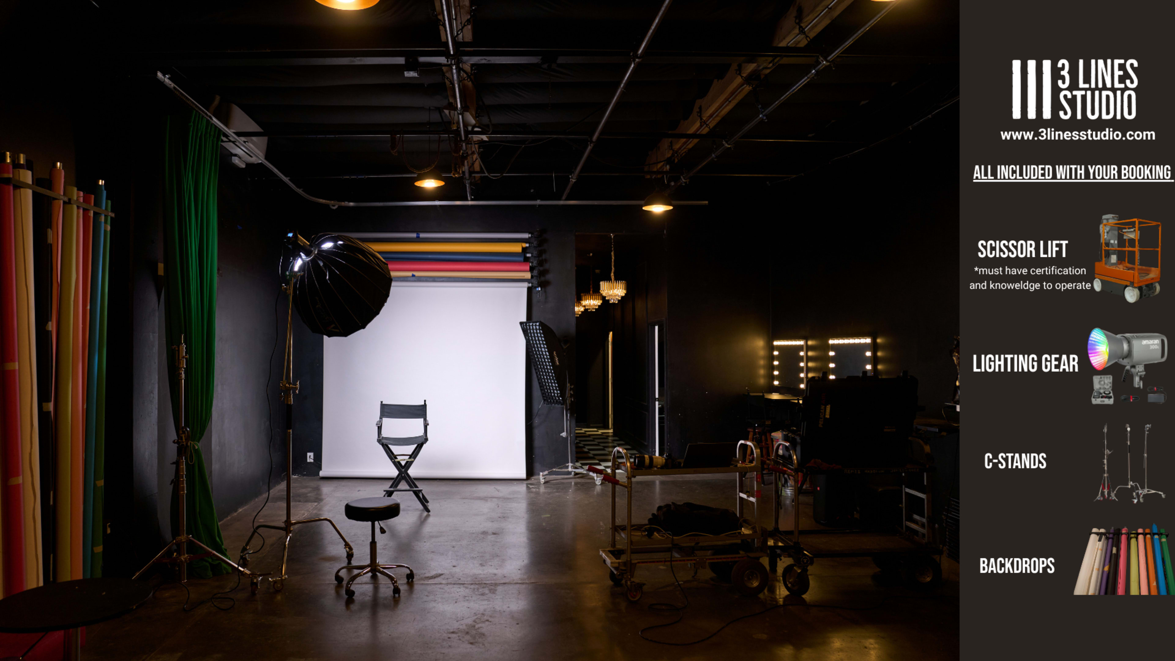 The image shows a photography studio setup with a backdrop, lighting equipment, and various props arranged in an industrial space.