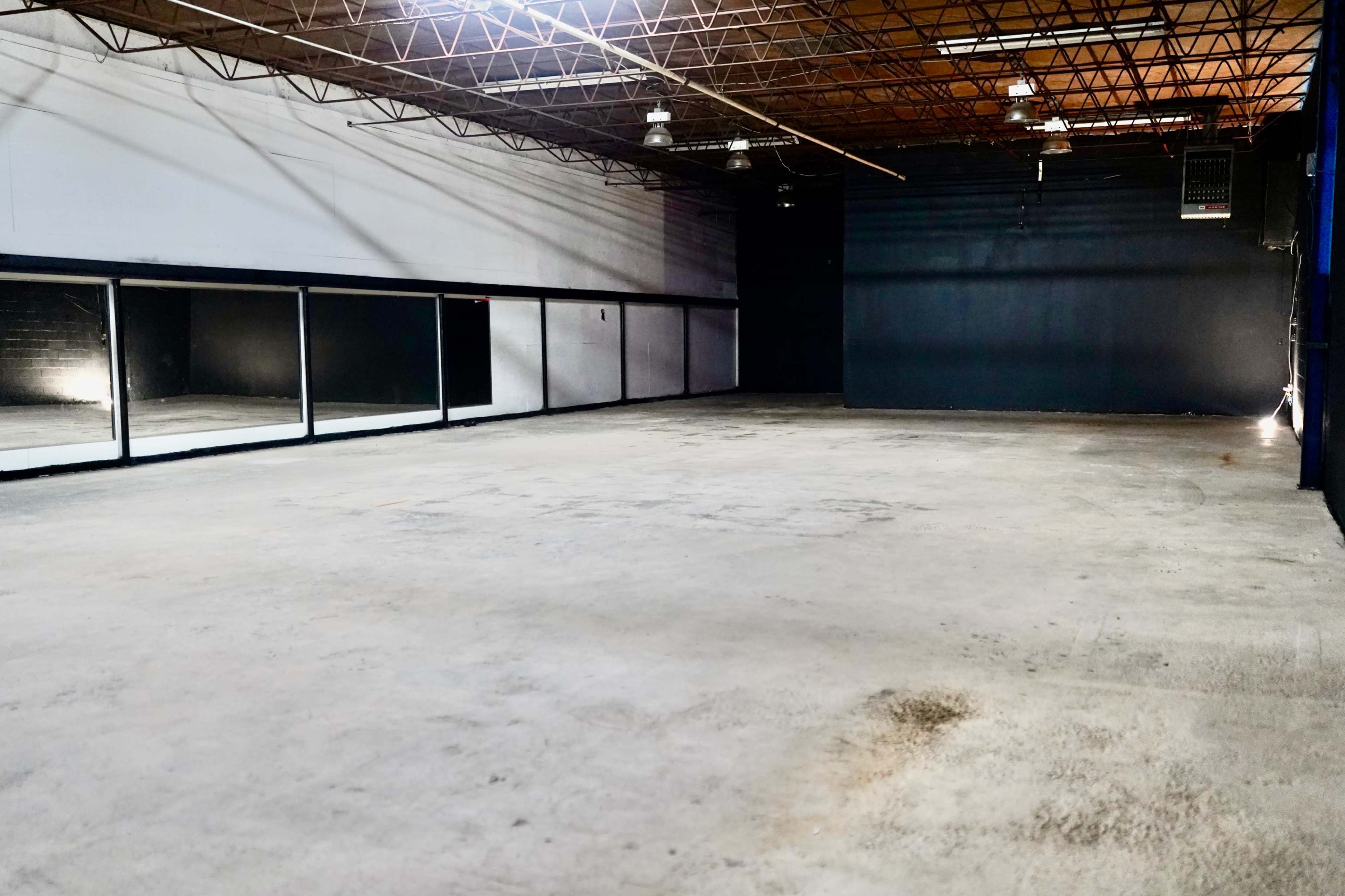 The image shows a large, empty industrial space with concrete floors and a ceiling supported by exposed beams.