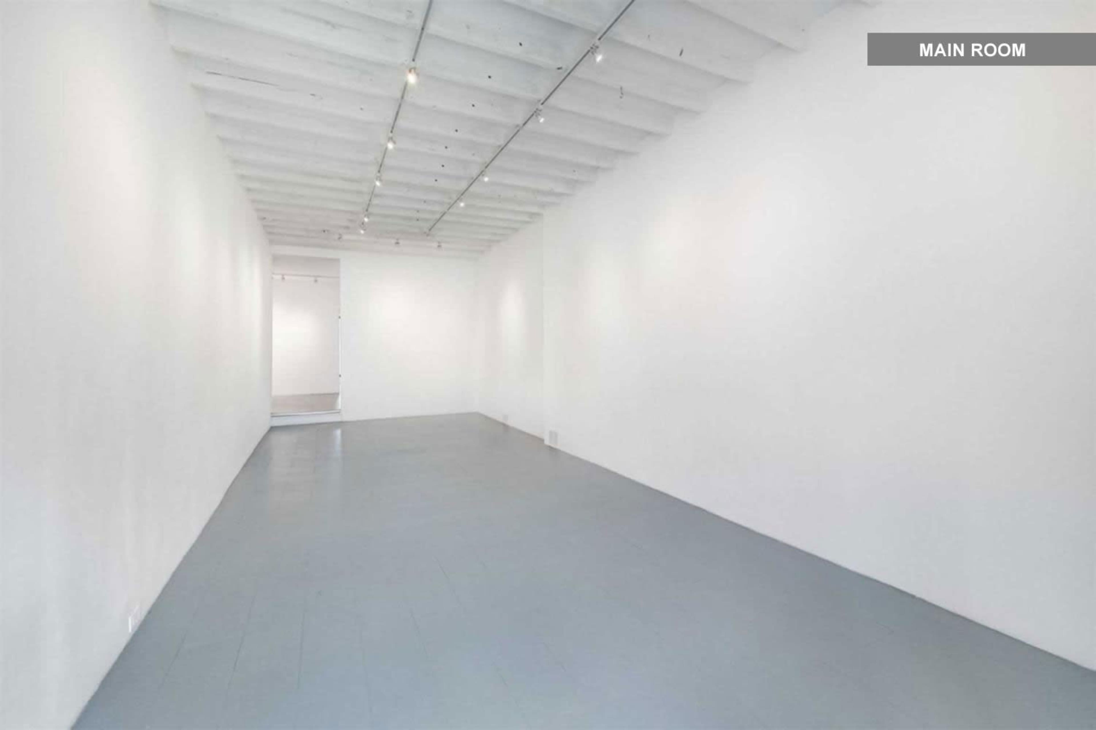 A spacious white room with a gray floor and exposed ceiling beams.