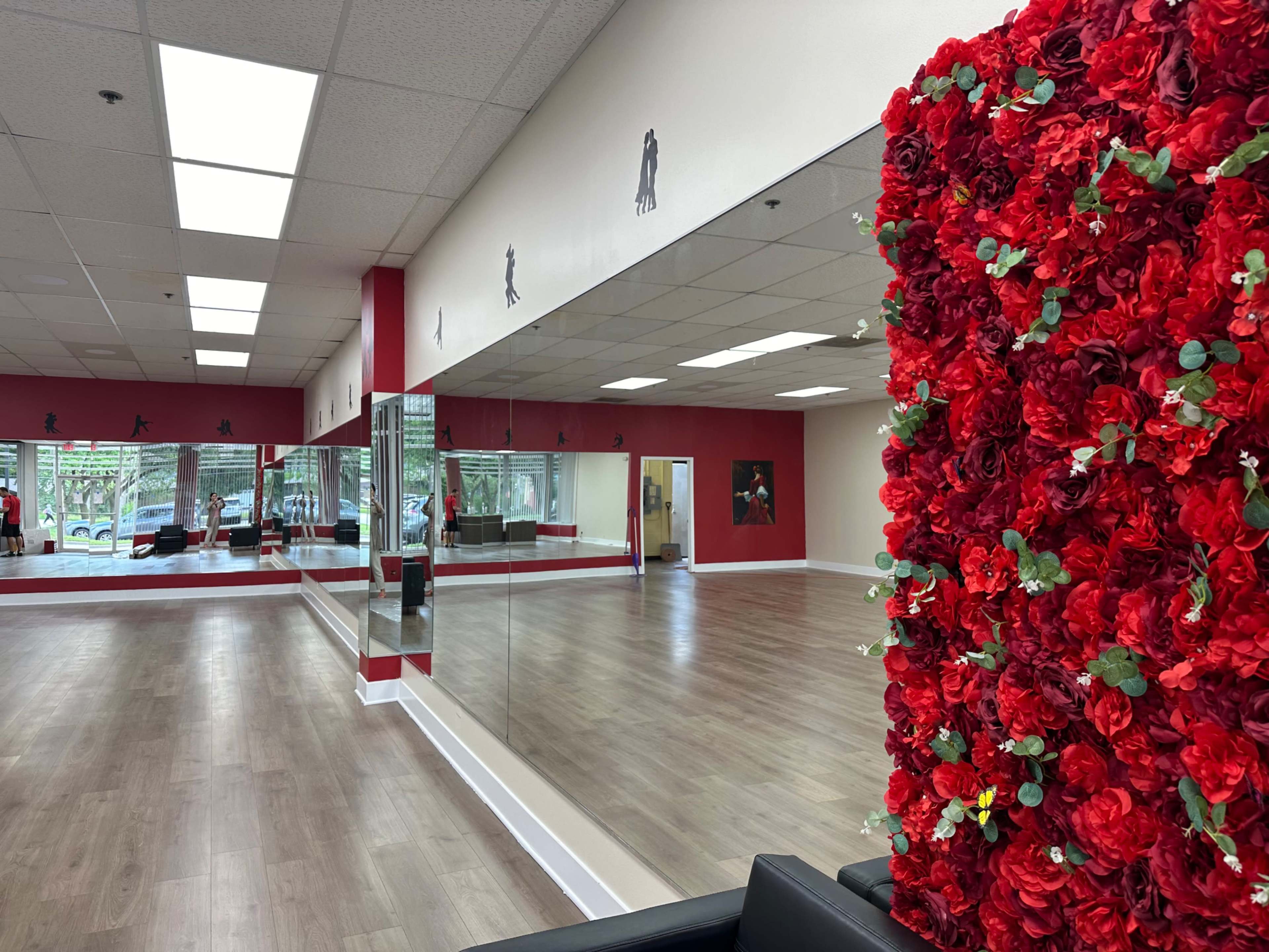 A dance studio featuring a large mirrored wall and a decorative red floral installation.