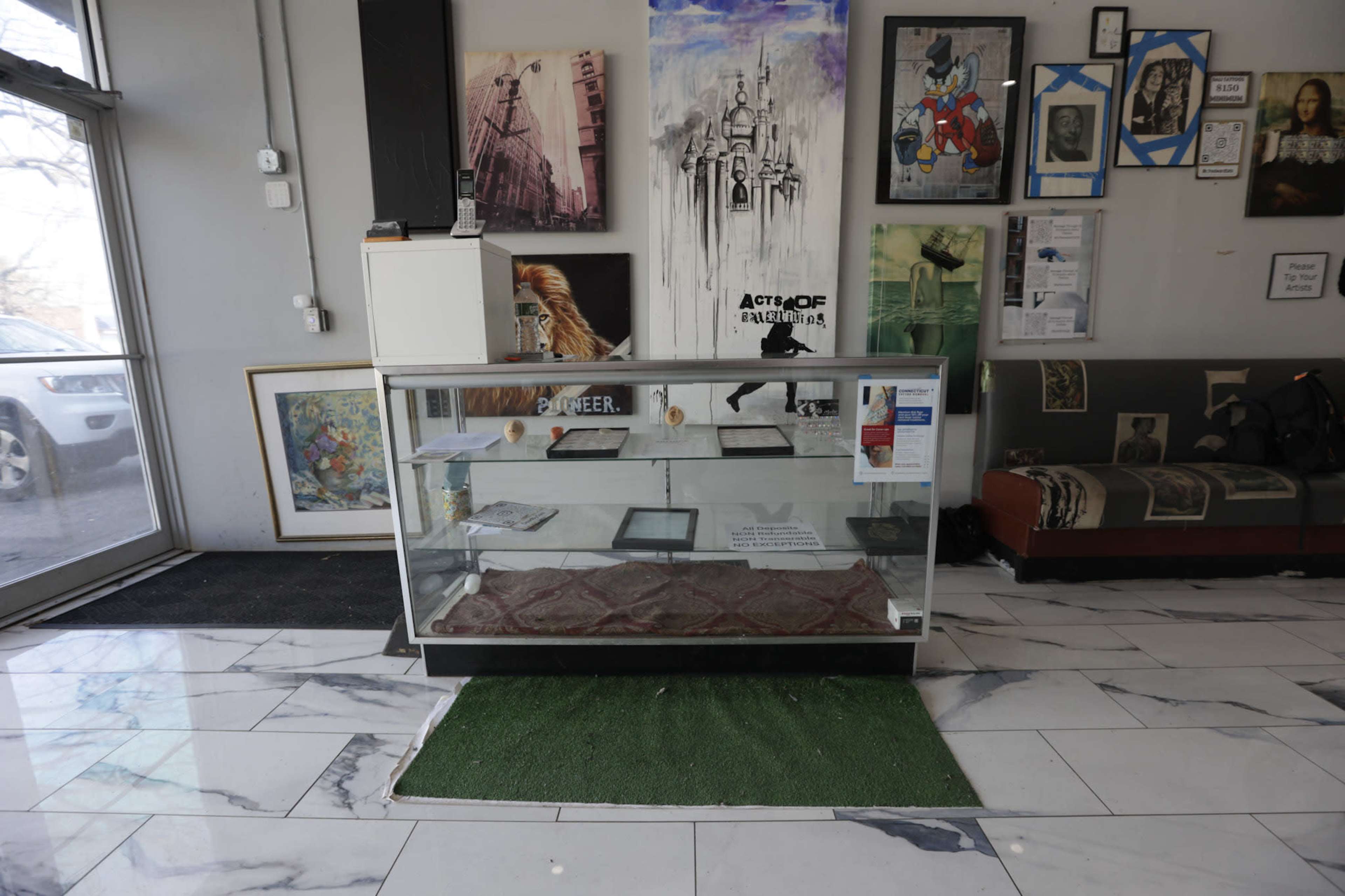 A glass display case surrounded by artwork and a seating area in a gallery or studio space.