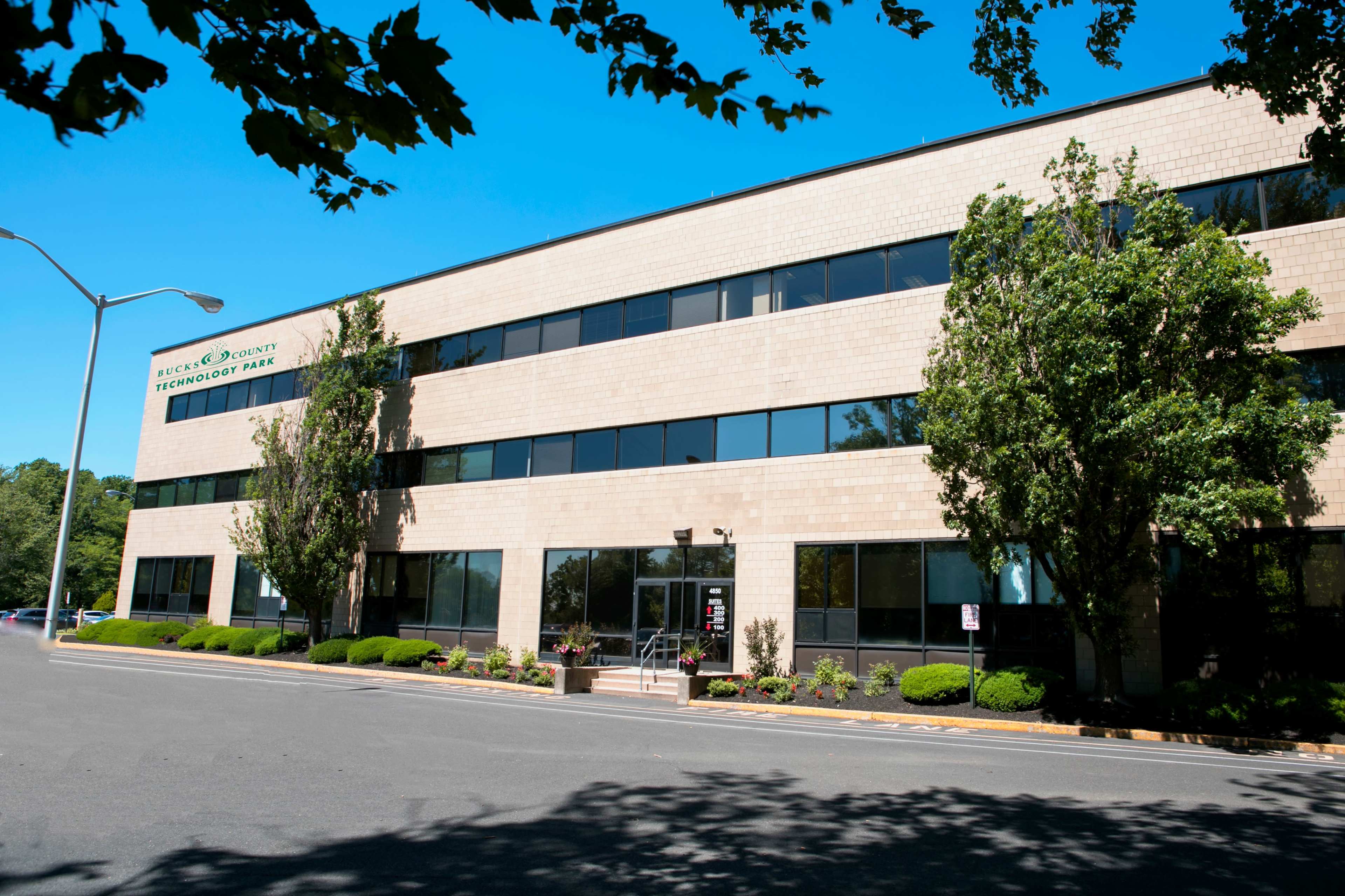 A modern, three-story office building with large windows and manicured landscaping in front.