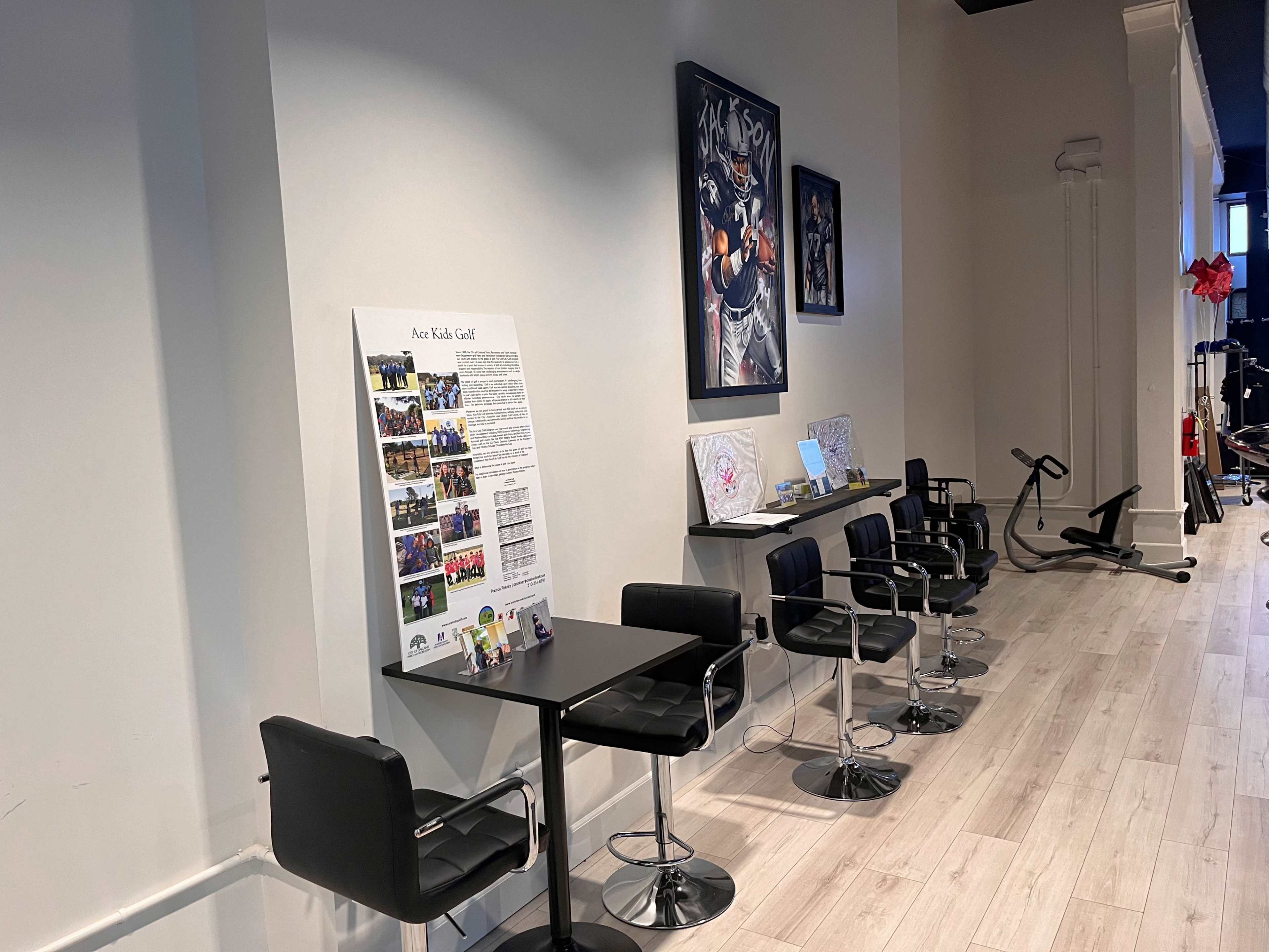 A modern interior space with black bar stools and tables, a promotional display board, and artwork on the walls.