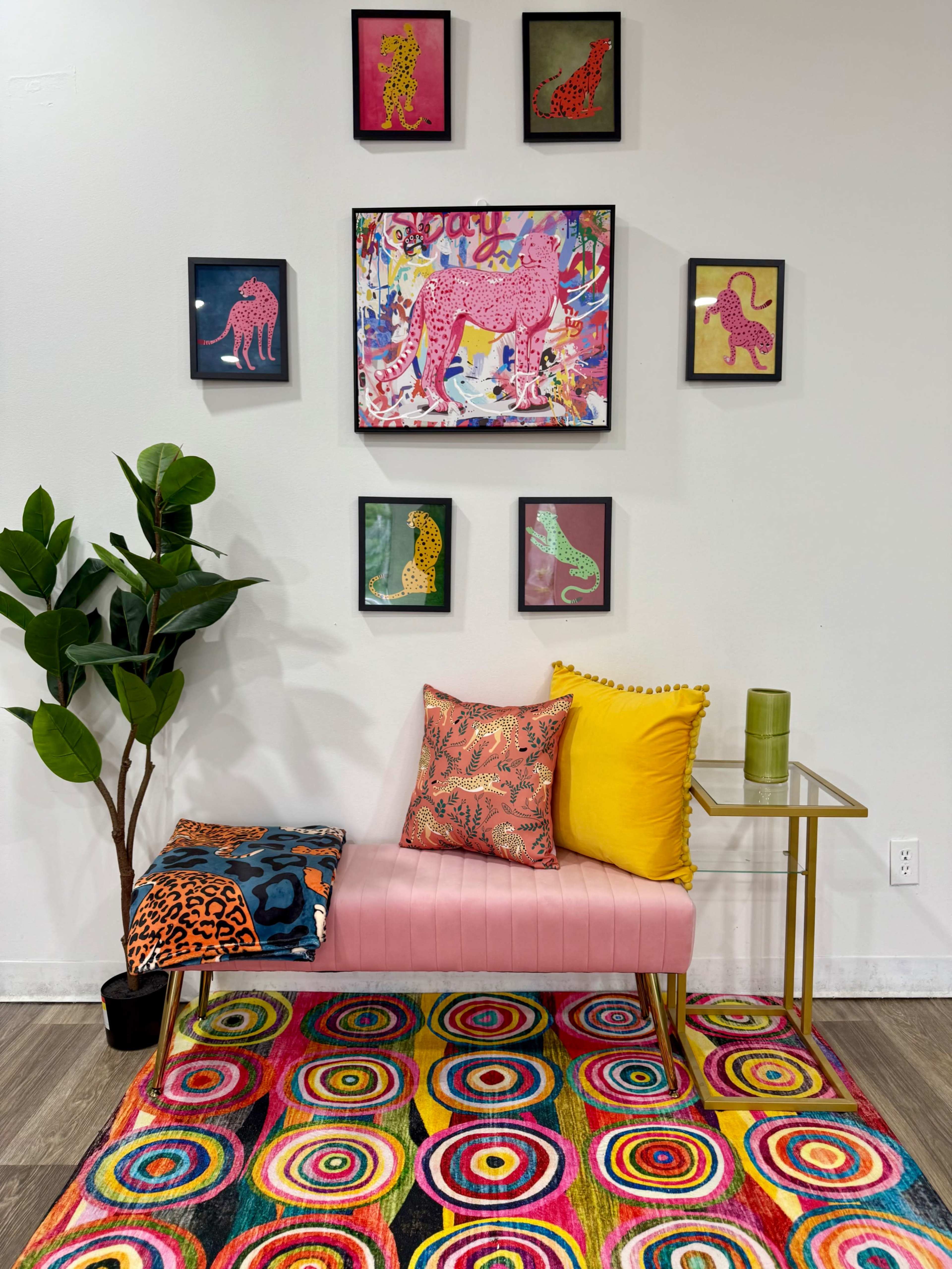 A pink bench is positioned against a wall adorned with colorful animal-themed artwork, surrounded by a vibrant circular-patterned rug and a potted plant.