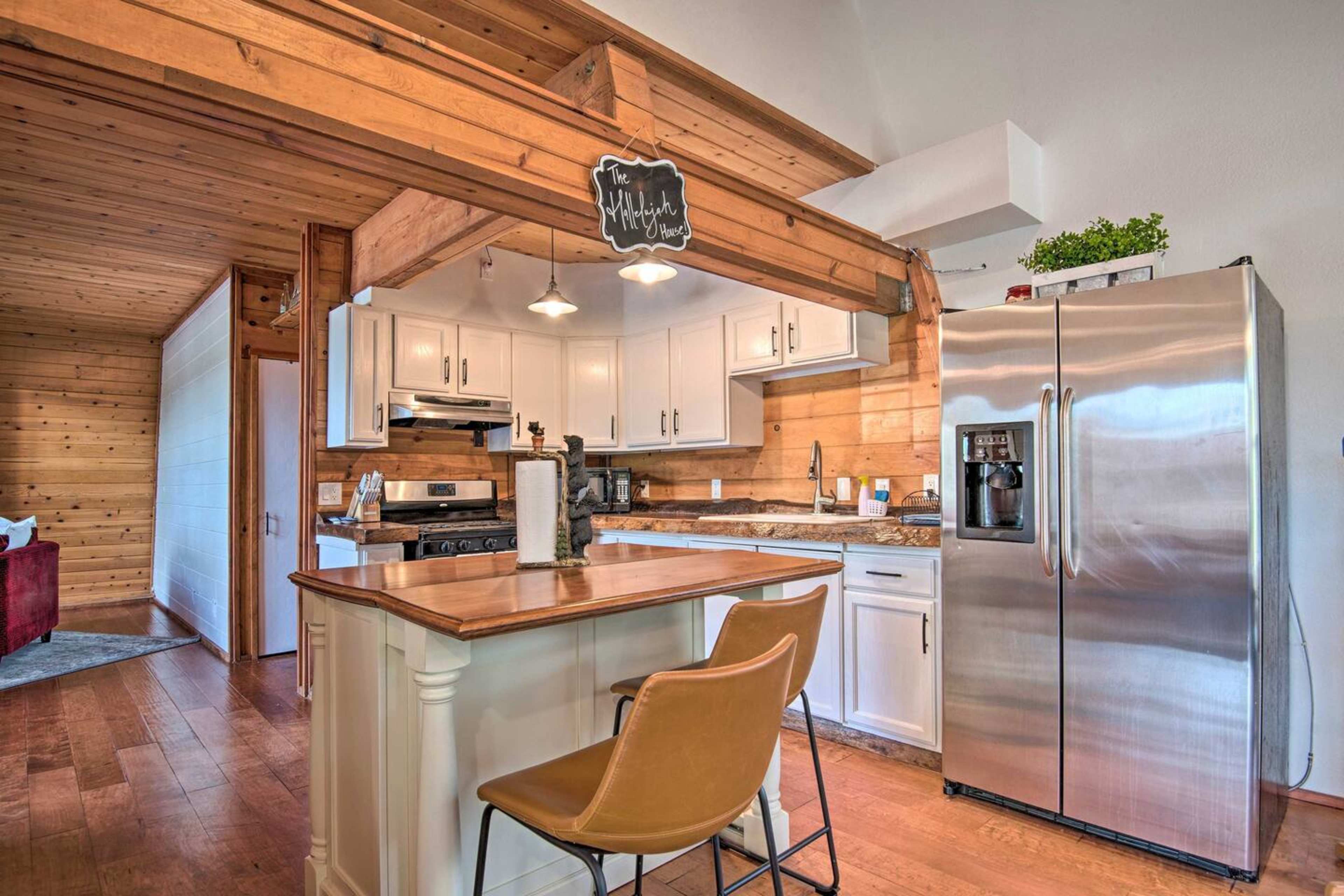 A modern kitchen features white cabinets, a granite countertop, stainless steel appliances, and a wooden beam overhead.