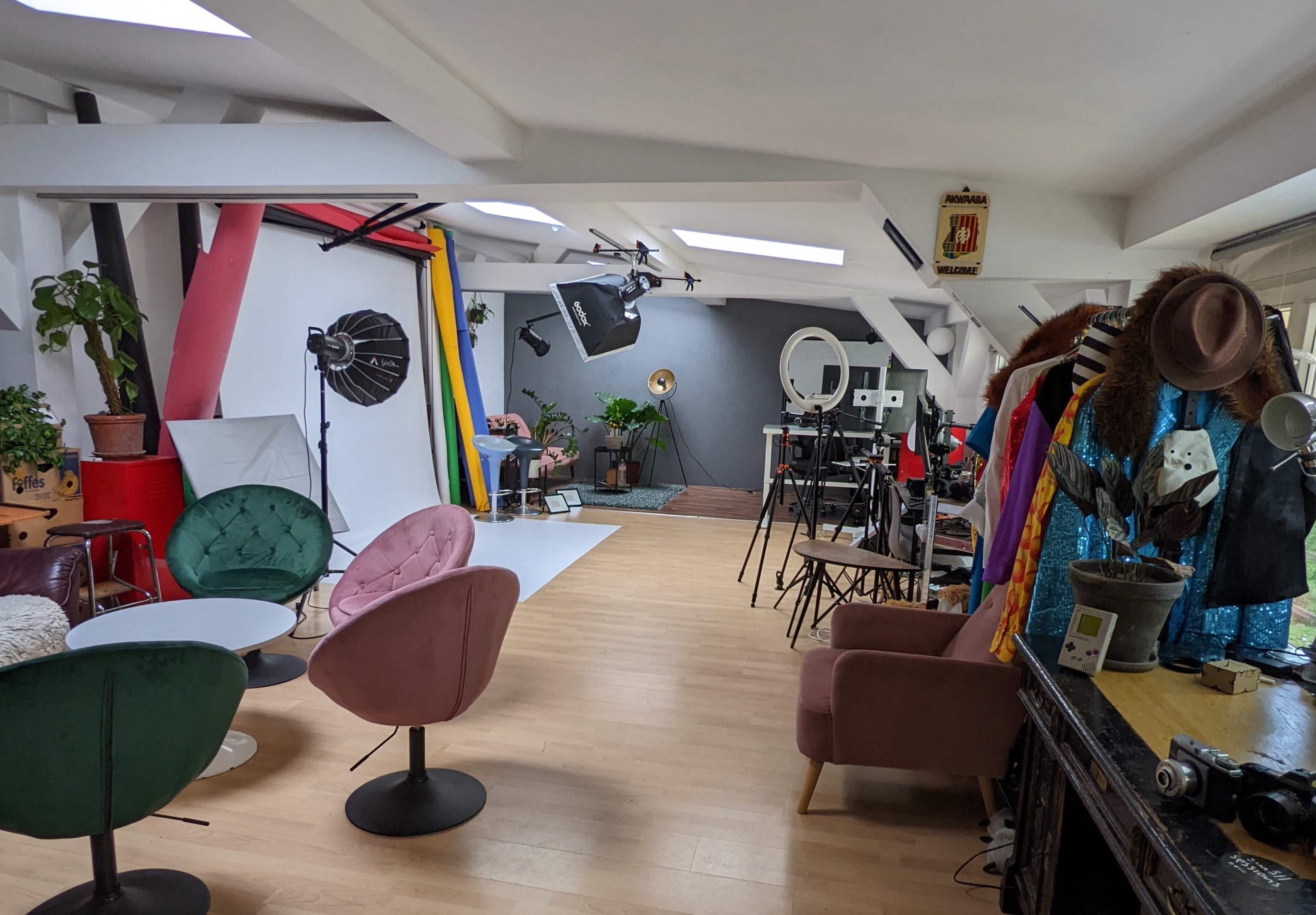 A photography studio featuring various backdrops, lighting equipment, and colorful costumes displayed on a rack.