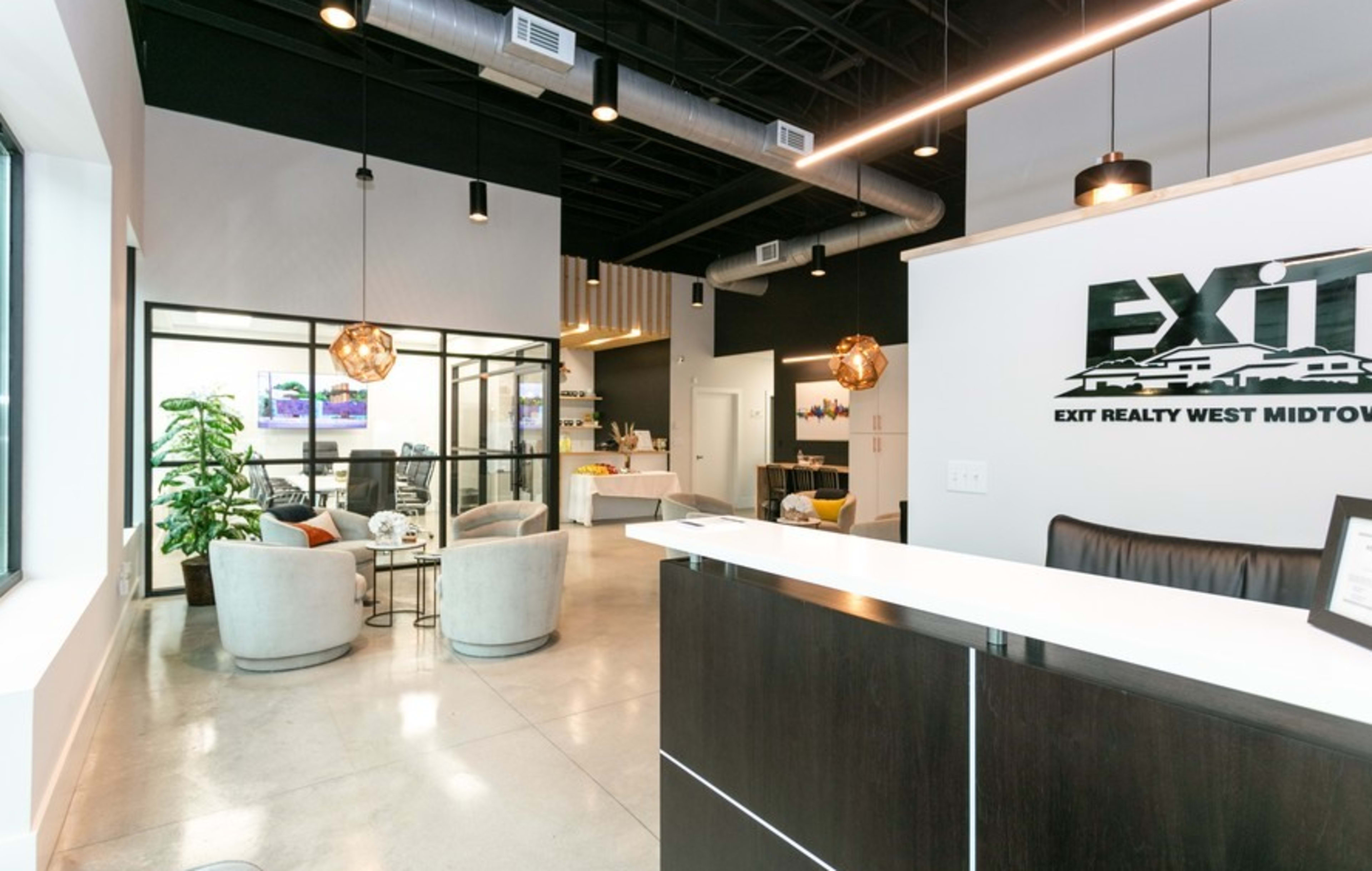A modern office reception area with a front desk, seating arrangements, and a glass-walled meeting room.