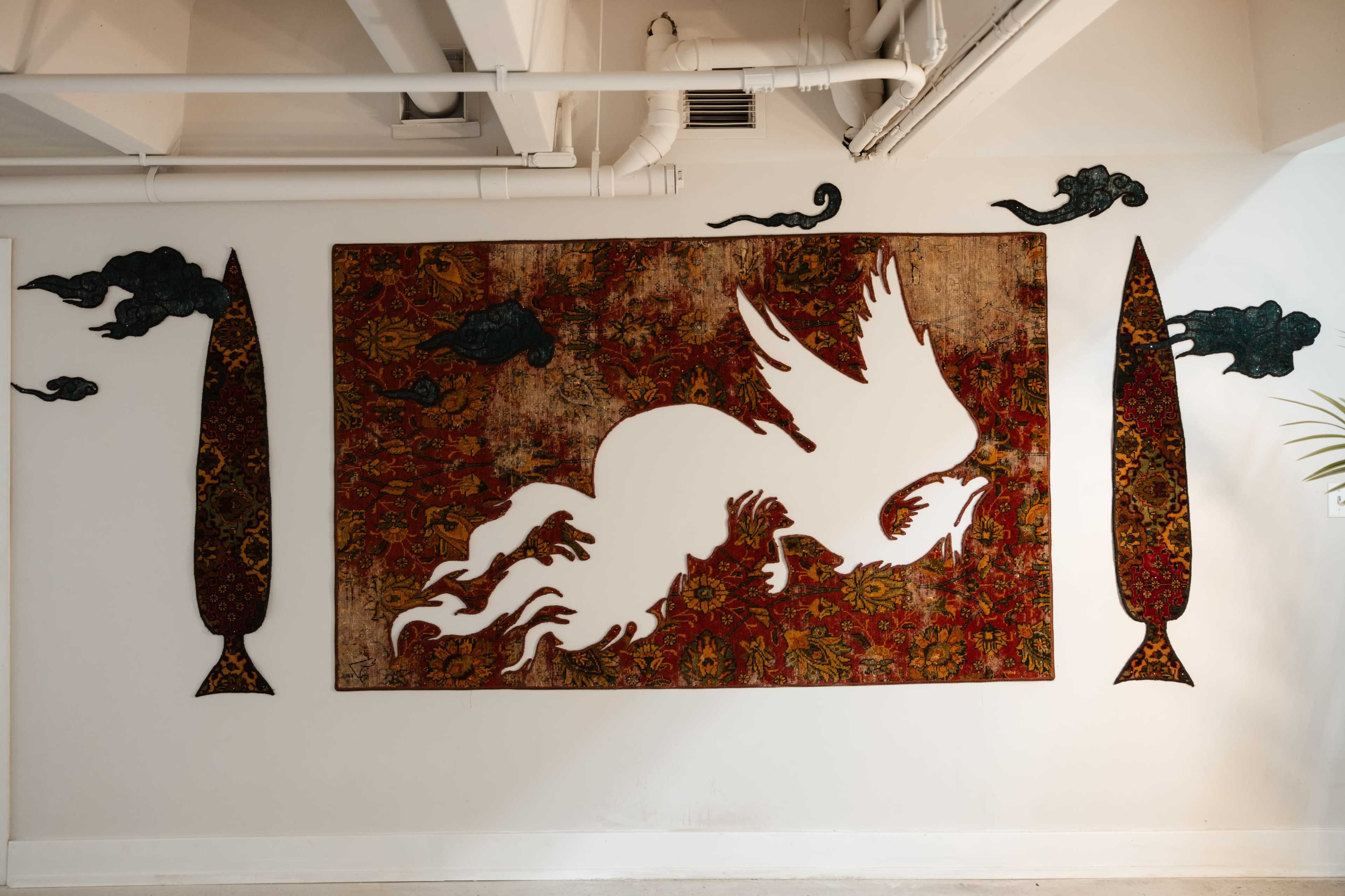 A large, abstract art piece featuring a white silhouette of a mythical creature on a textured red and gold background is displayed on a wall alongside two tall, decorative panels.