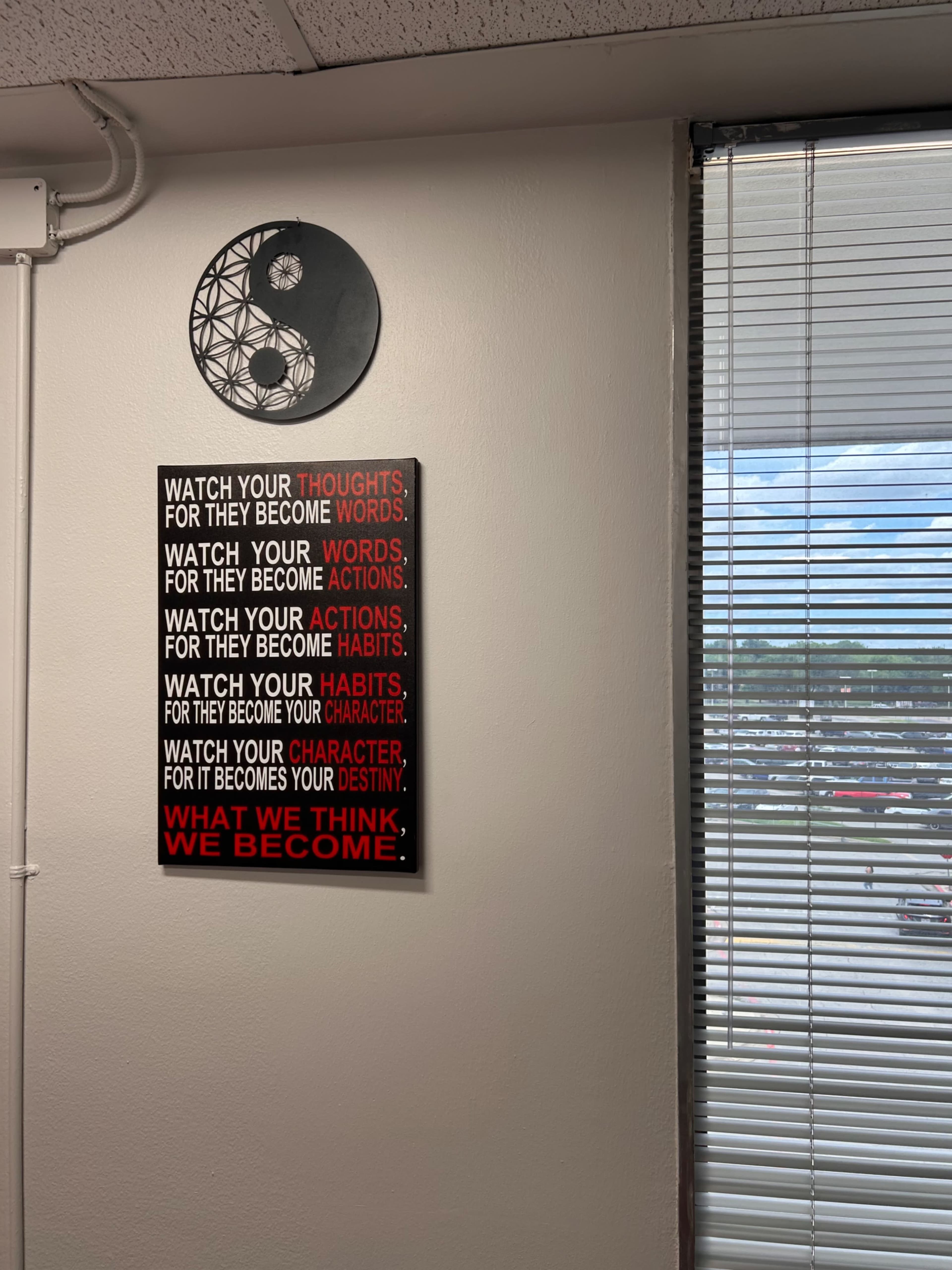 The image shows a wall with a motivational poster featuring the phrases "Watch your thoughts," "Watch your words," "Watch your actions," "Watch your habits," and "Watch your character," alongside a circular yin-yang symbol.