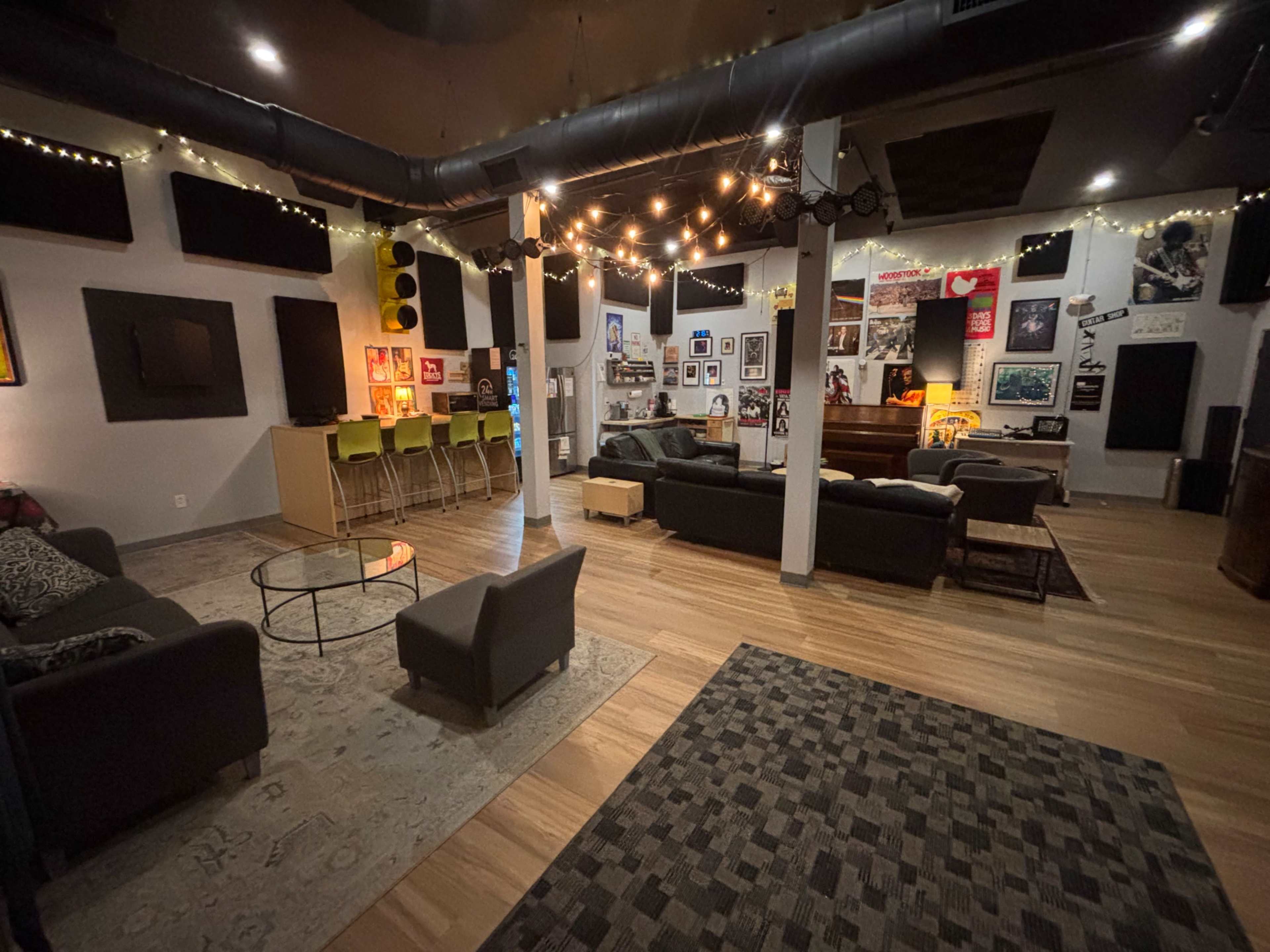 The room features a spacious layout with a lounge area, a bar with high chairs, and walls adorned with various framed posters and artwork.