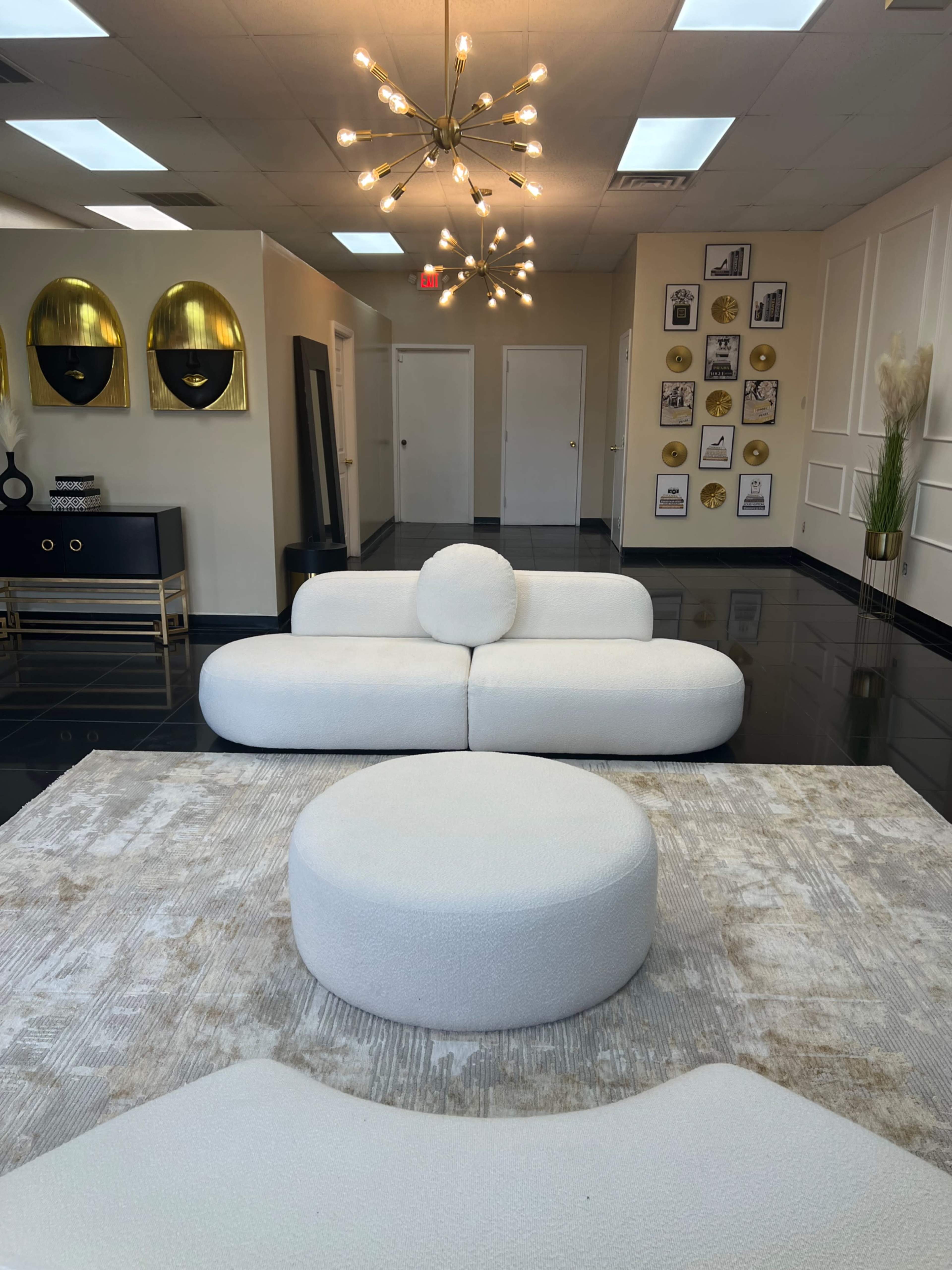 A modern interior with a white sofa and round coffee table, highlighted by a unique light fixture and decorative wall art.