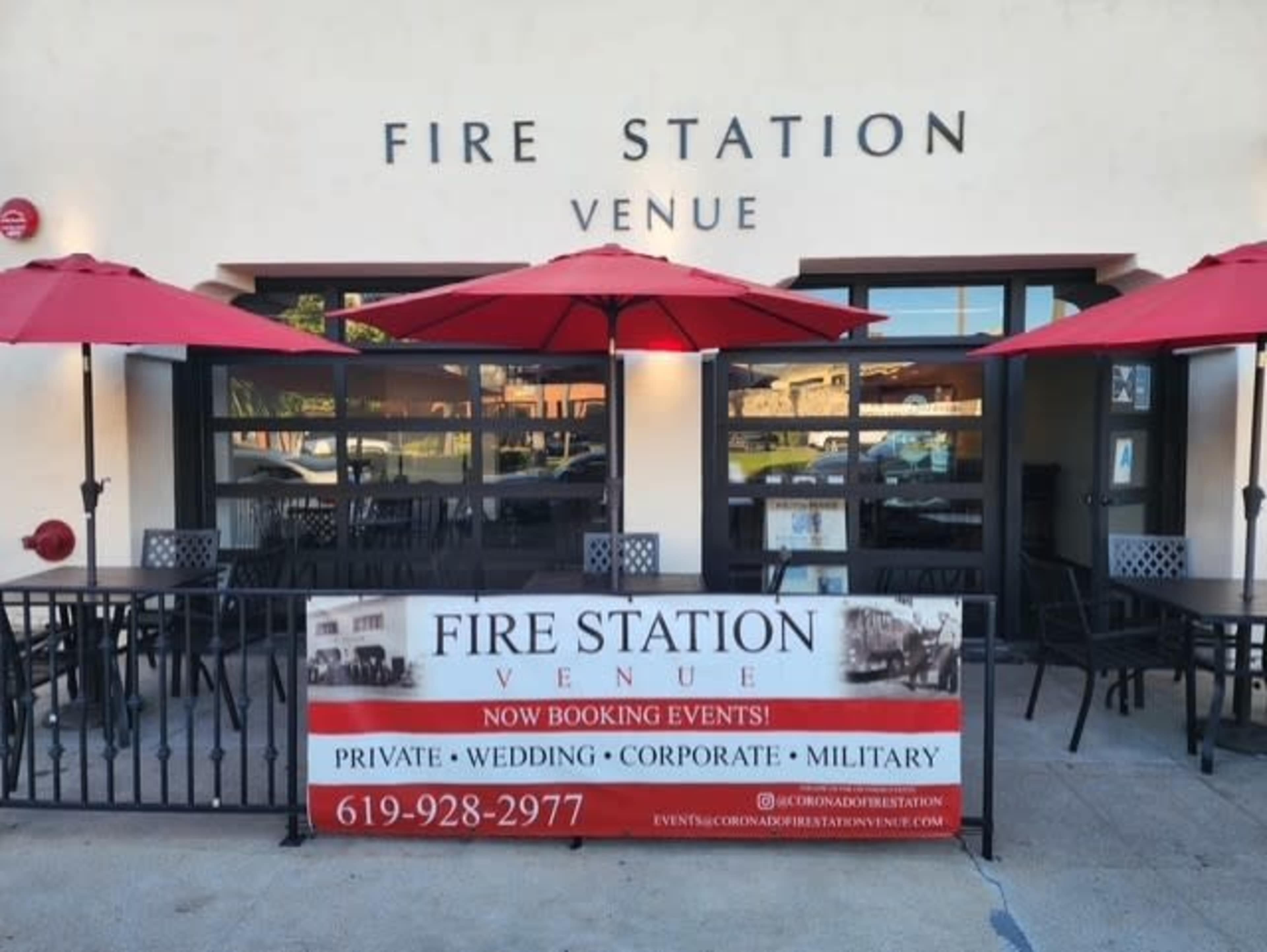 A building named "Fire Station Venue" features outdoor tables with red umbrellas and a banner promoting event bookings.
