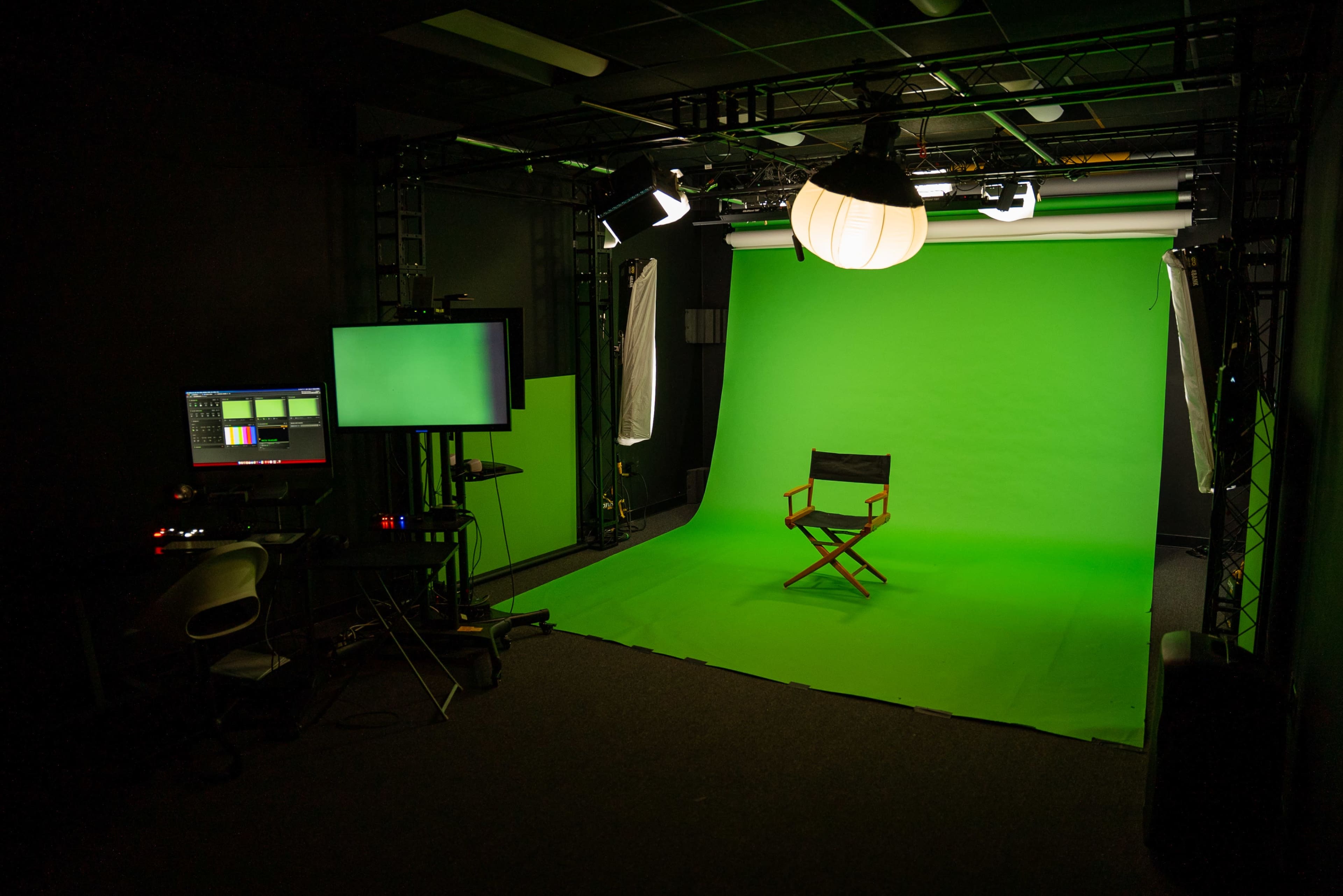 A green screen studio setup with a director's chair positioned in front of an illuminated green backdrop.
