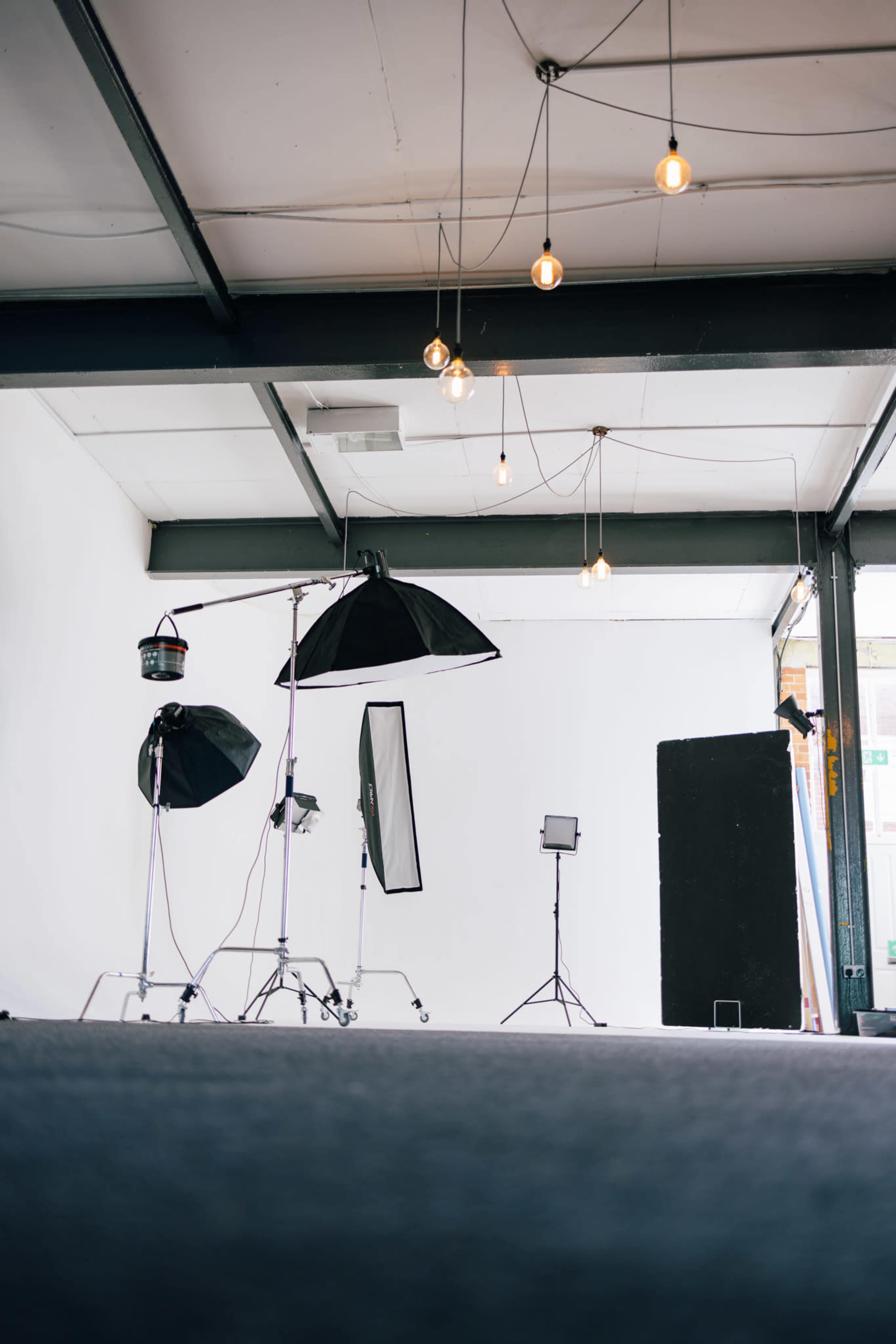 A photography studio is set up with various lighting equipment and a plain white backdrop.