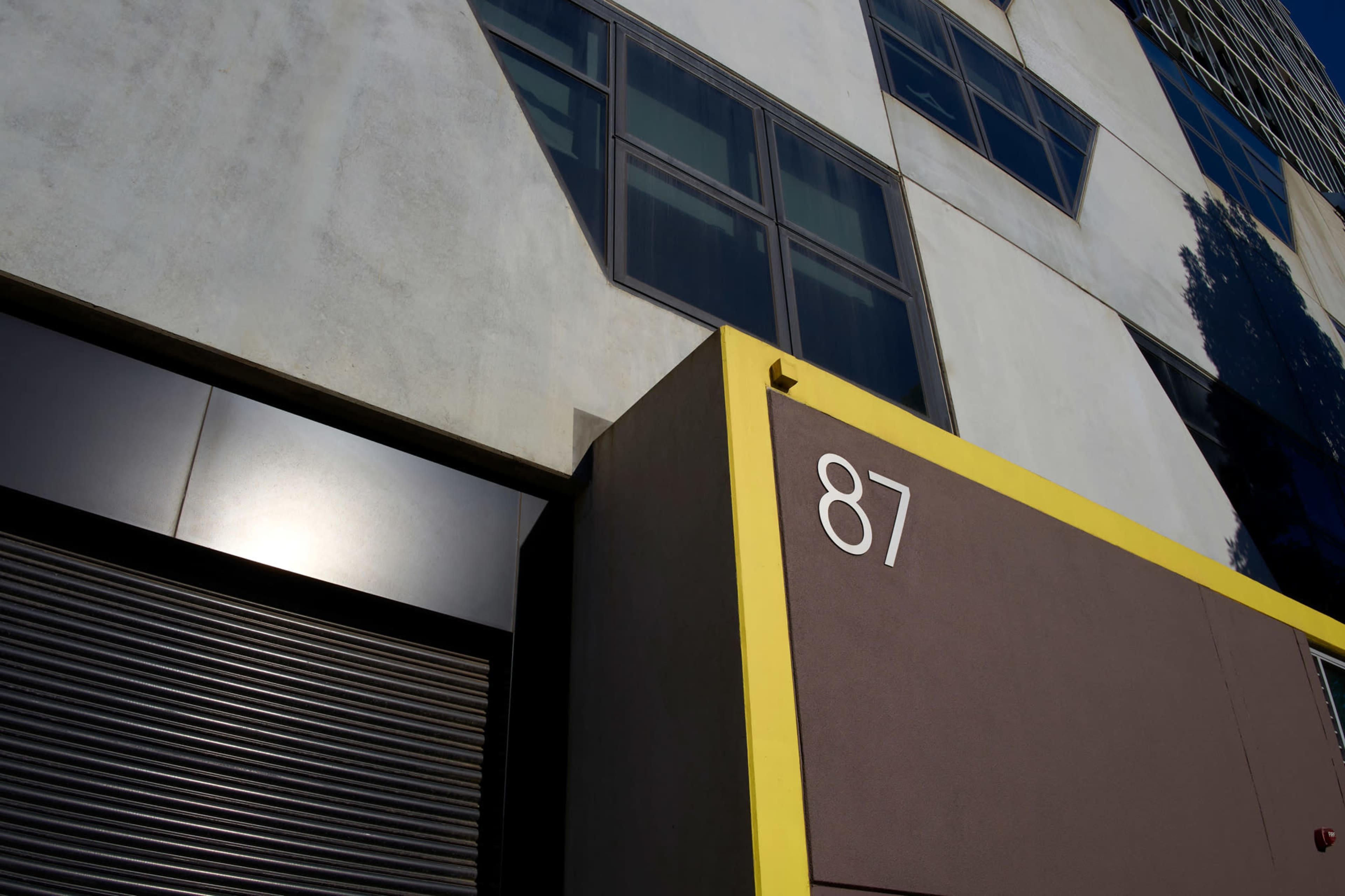 A modern building facade featuring geometric shapes, with a prominent number "87" displayed on a section of the wall.
