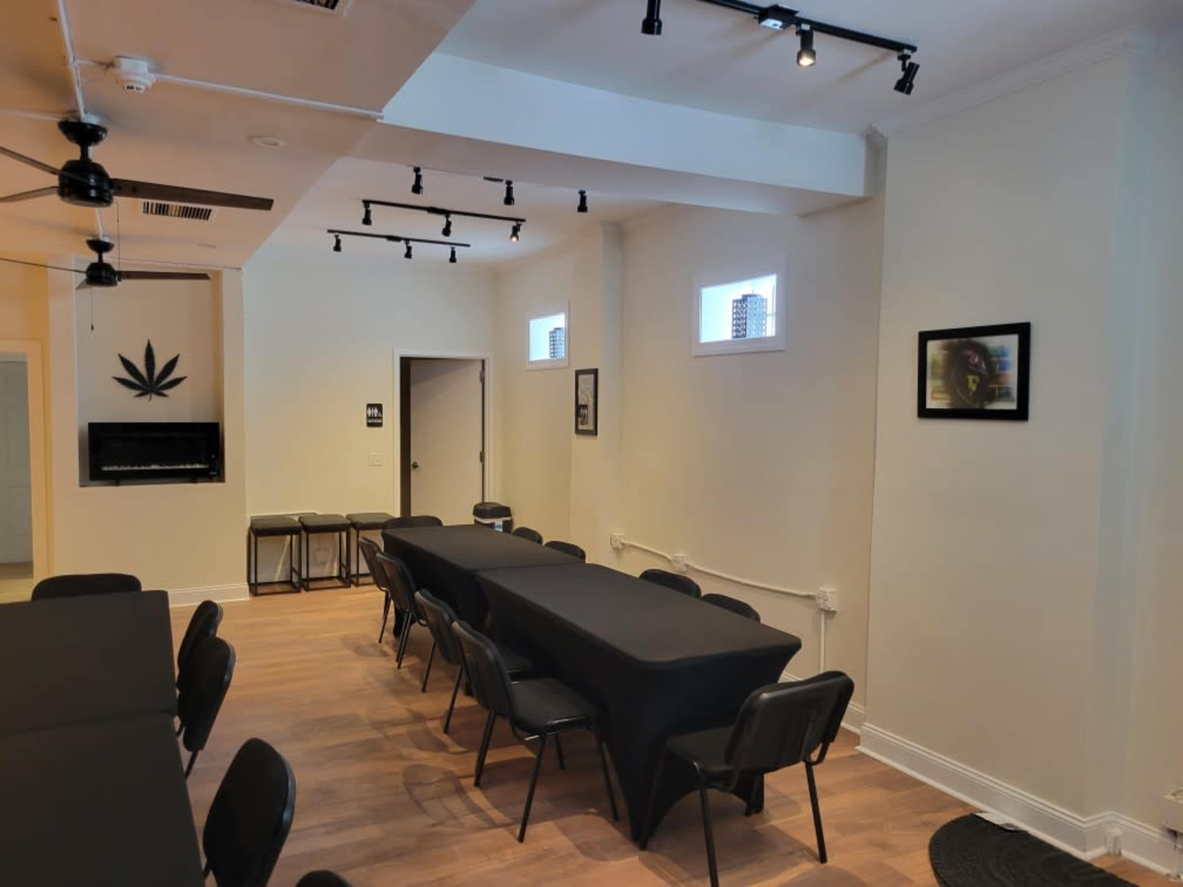 A conference room with several black tables arranged in rows, black chairs, and framed artwork on the walls.