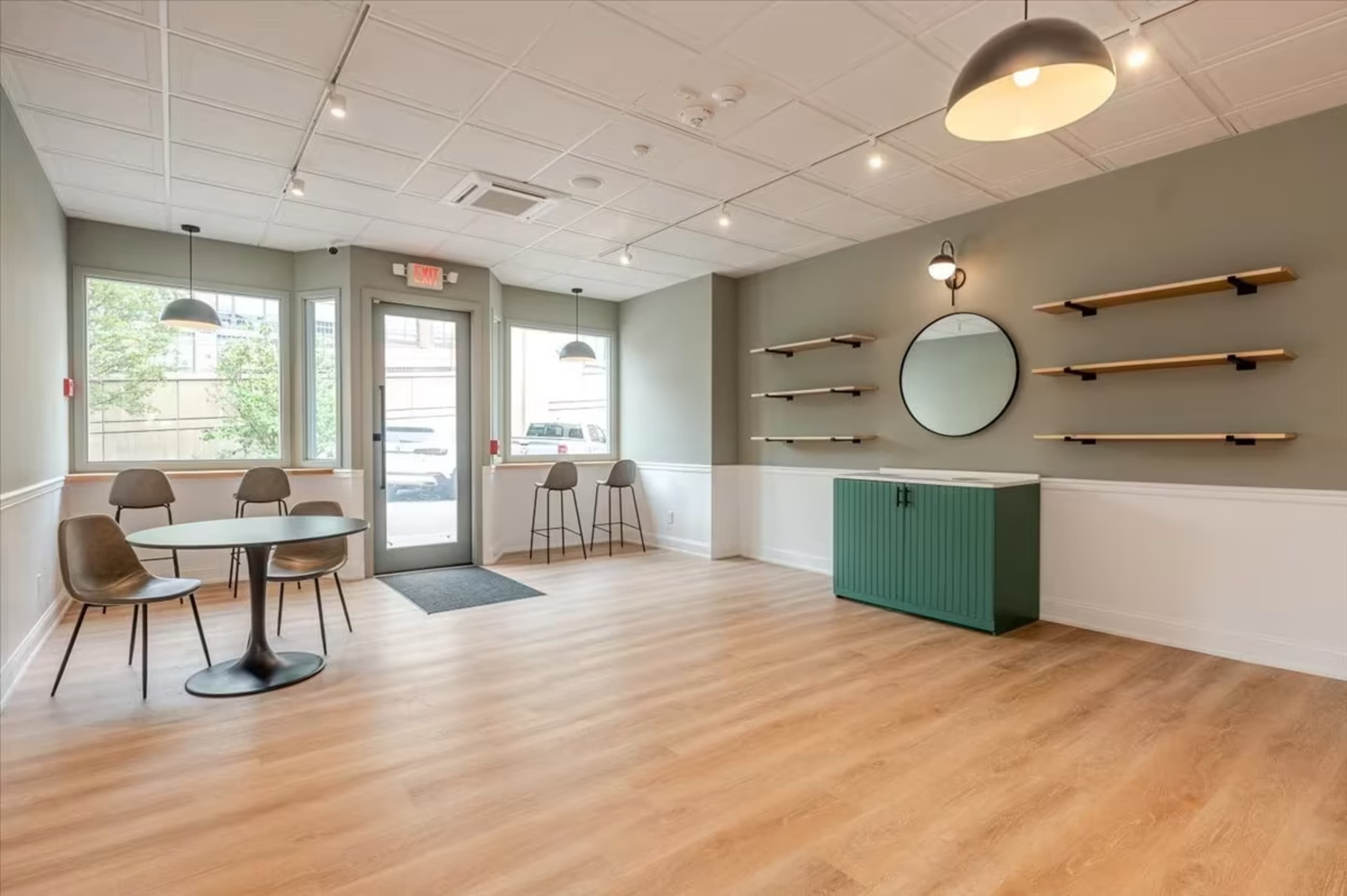 A modern, minimalist interior with a round mirror and shelves on the wall, featuring a table and four chairs in a light-filled room.